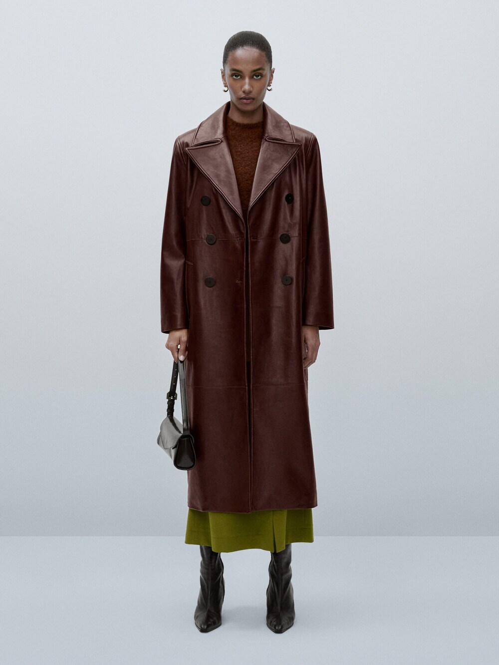 Massimo Dutti nappa leather trench in burgundy. Made from sheepskin leather. The long leather coat has a Double-breasted button fastening at the front with contrasting black buttons. Two side slit pockets. 