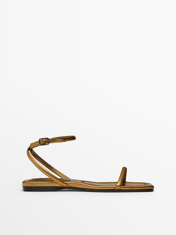 Flat gold leather sandals with crossover straps