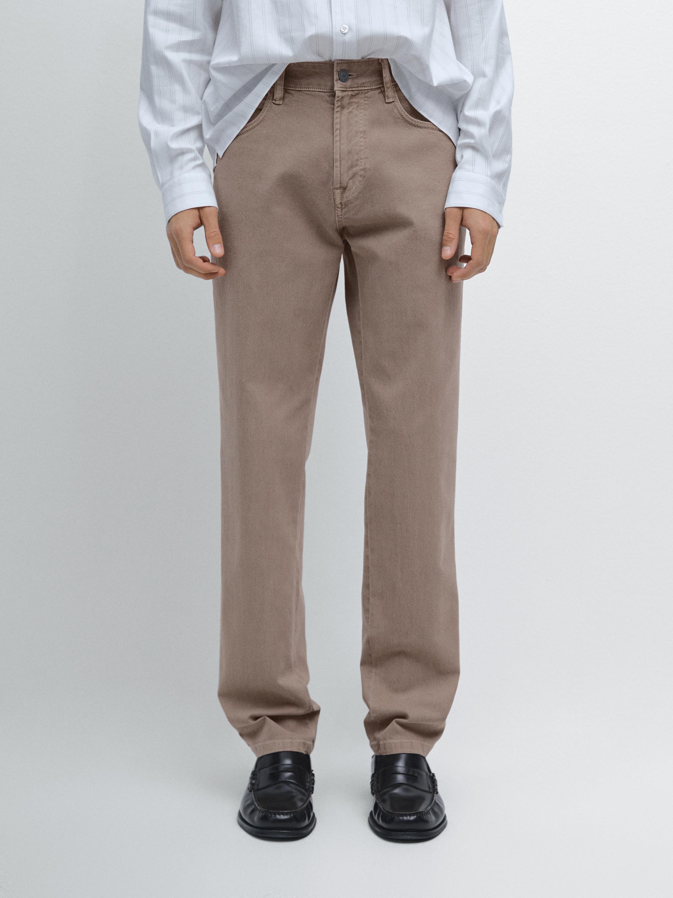 White shirt and straight-cut beige jeans set with side pockets and a front button.