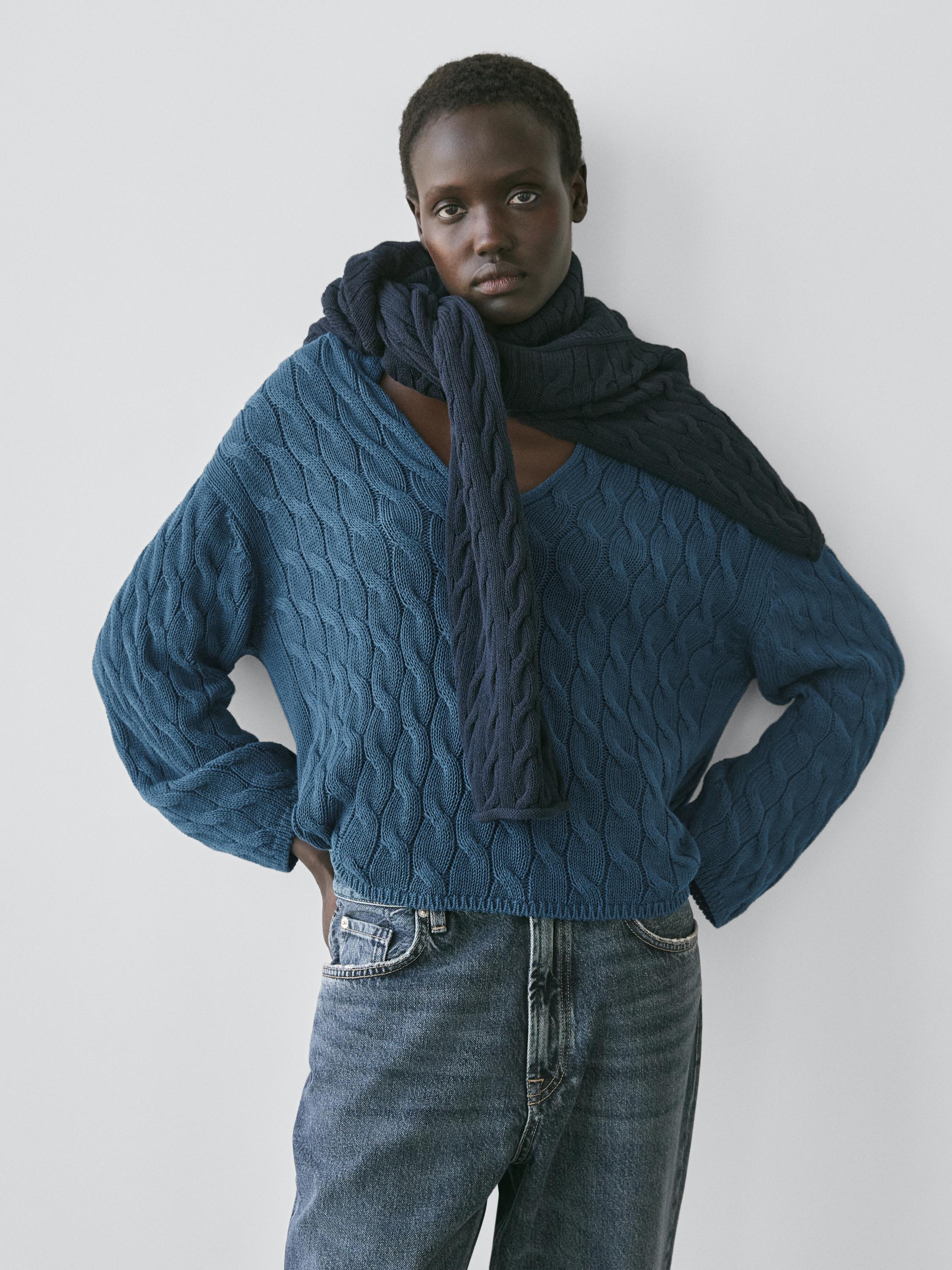 Ensemble pull bleu vif avec détails de nœuds et jean bleu.
