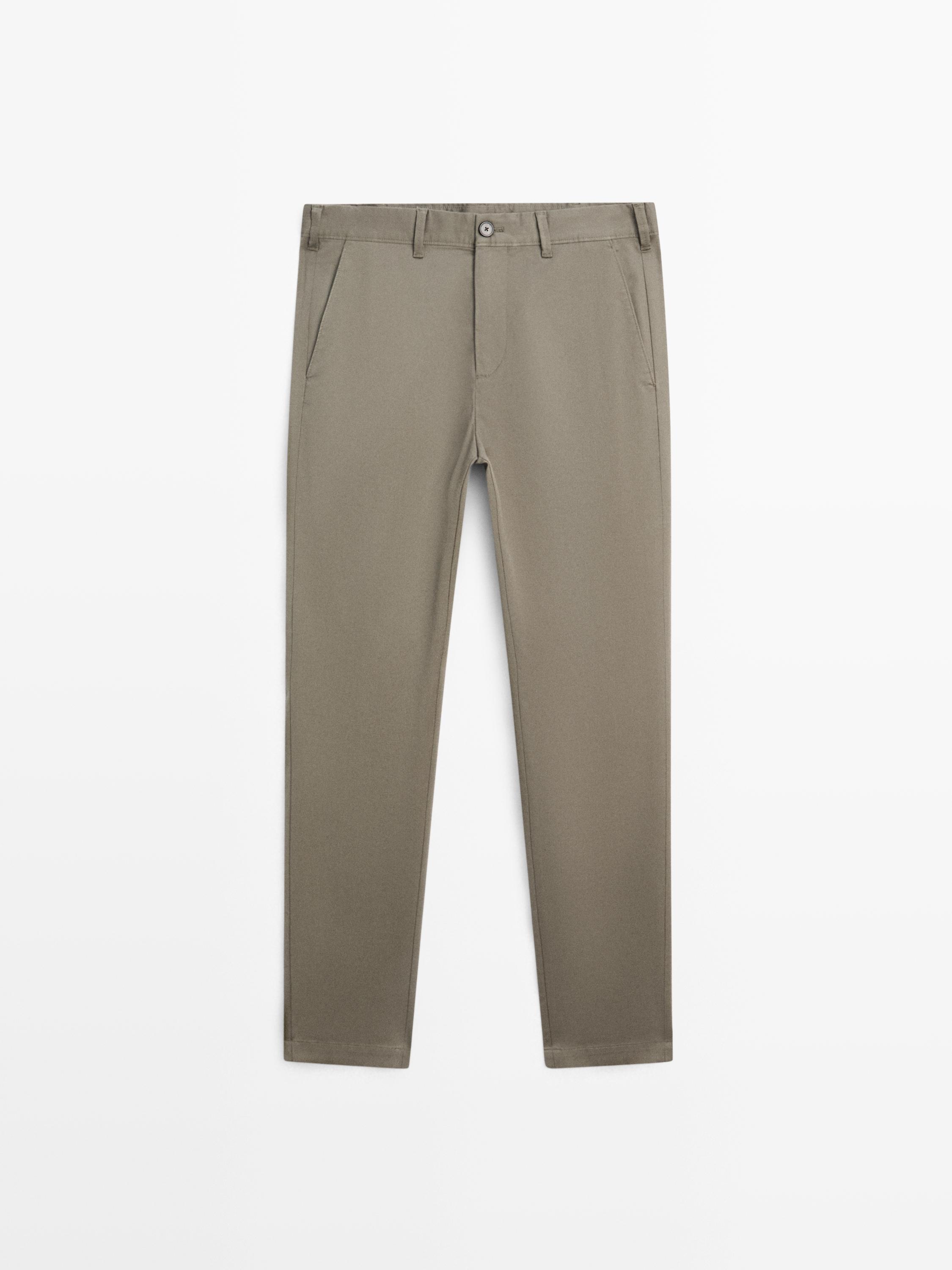 Front view of green slim-fit pants with side pockets and button closure.