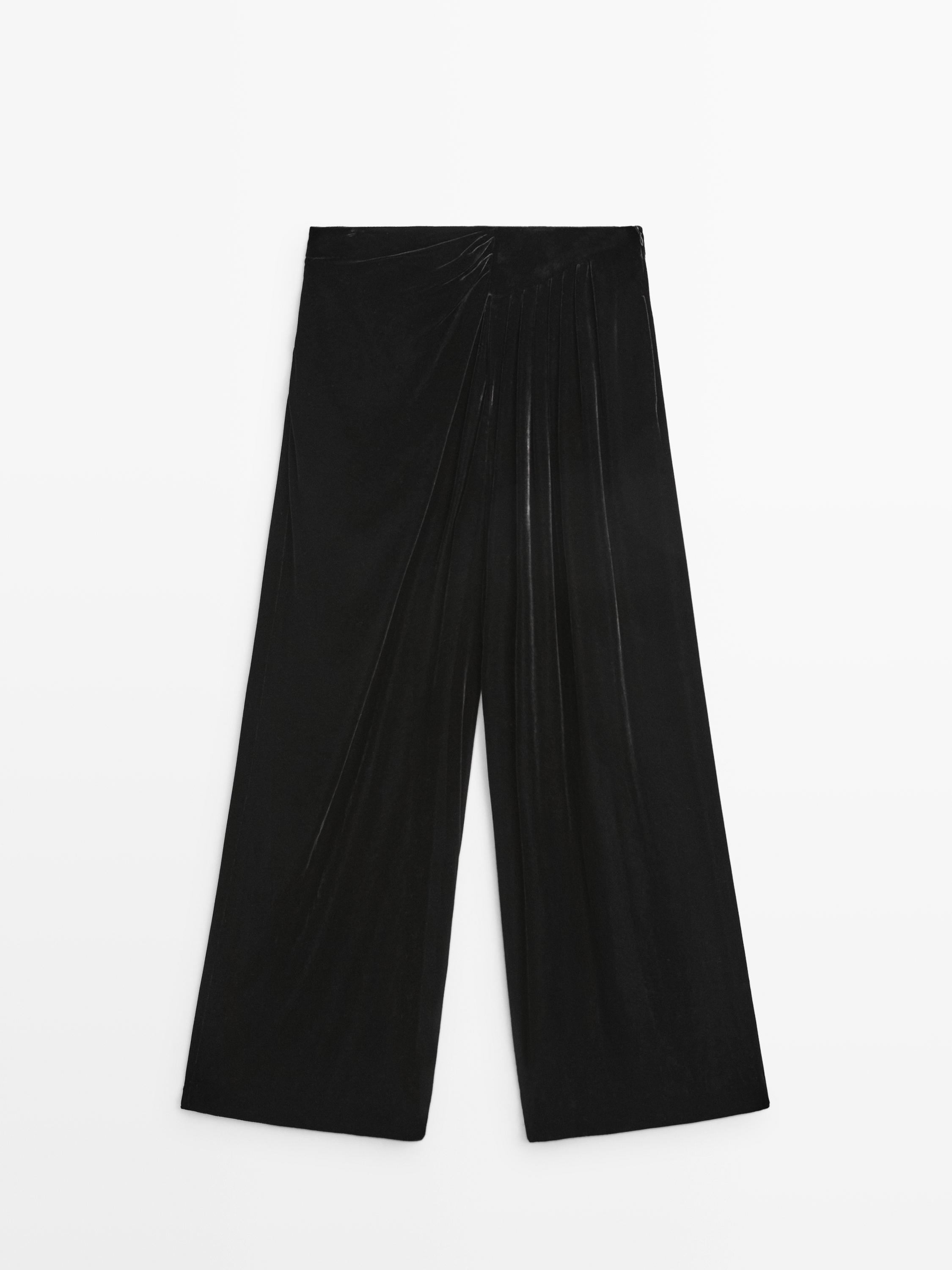 Vue de face d'un pantalon large noir avec détail de plis sur le haut.