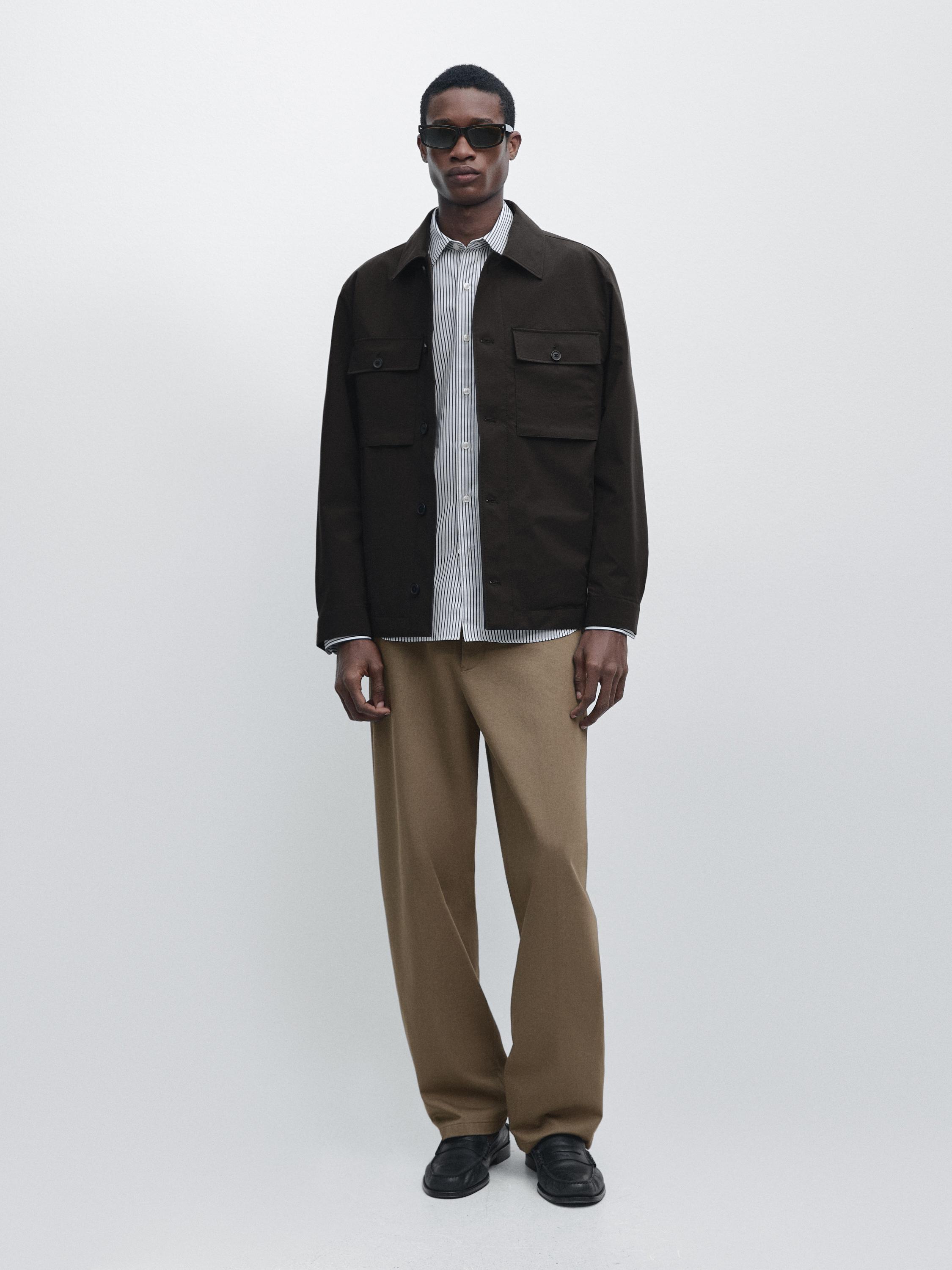 Chocolate jacket set with front pockets, striped shirt, and straight beige pants.