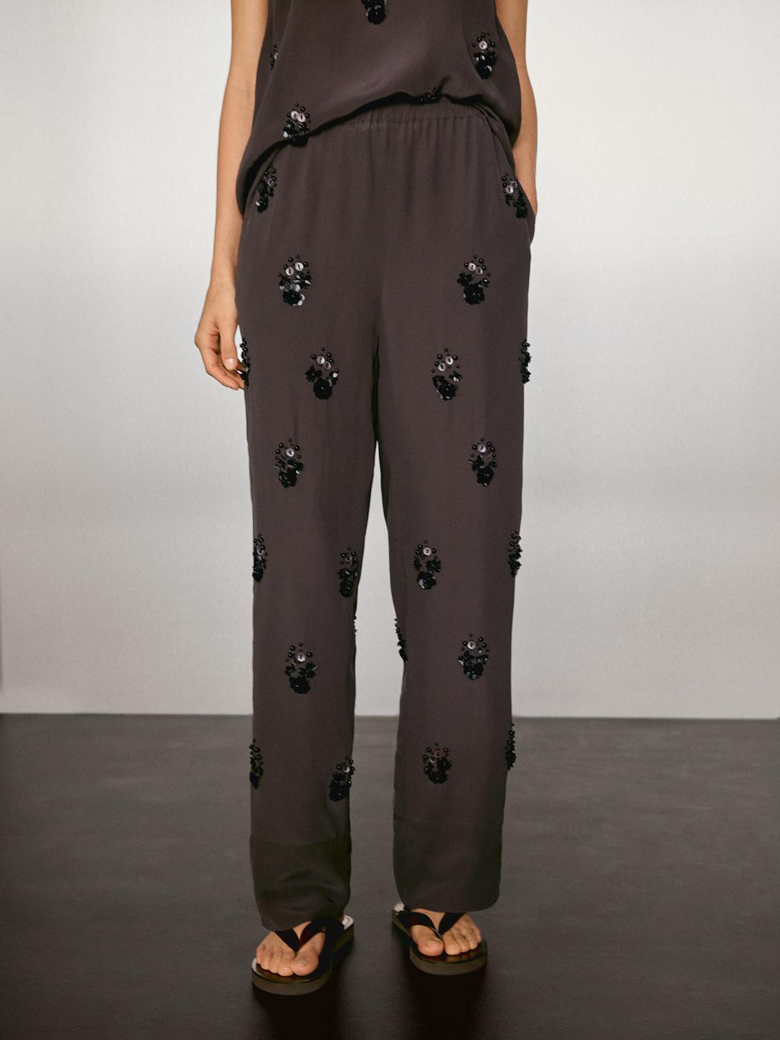 Flowing trousers with floral appliqués