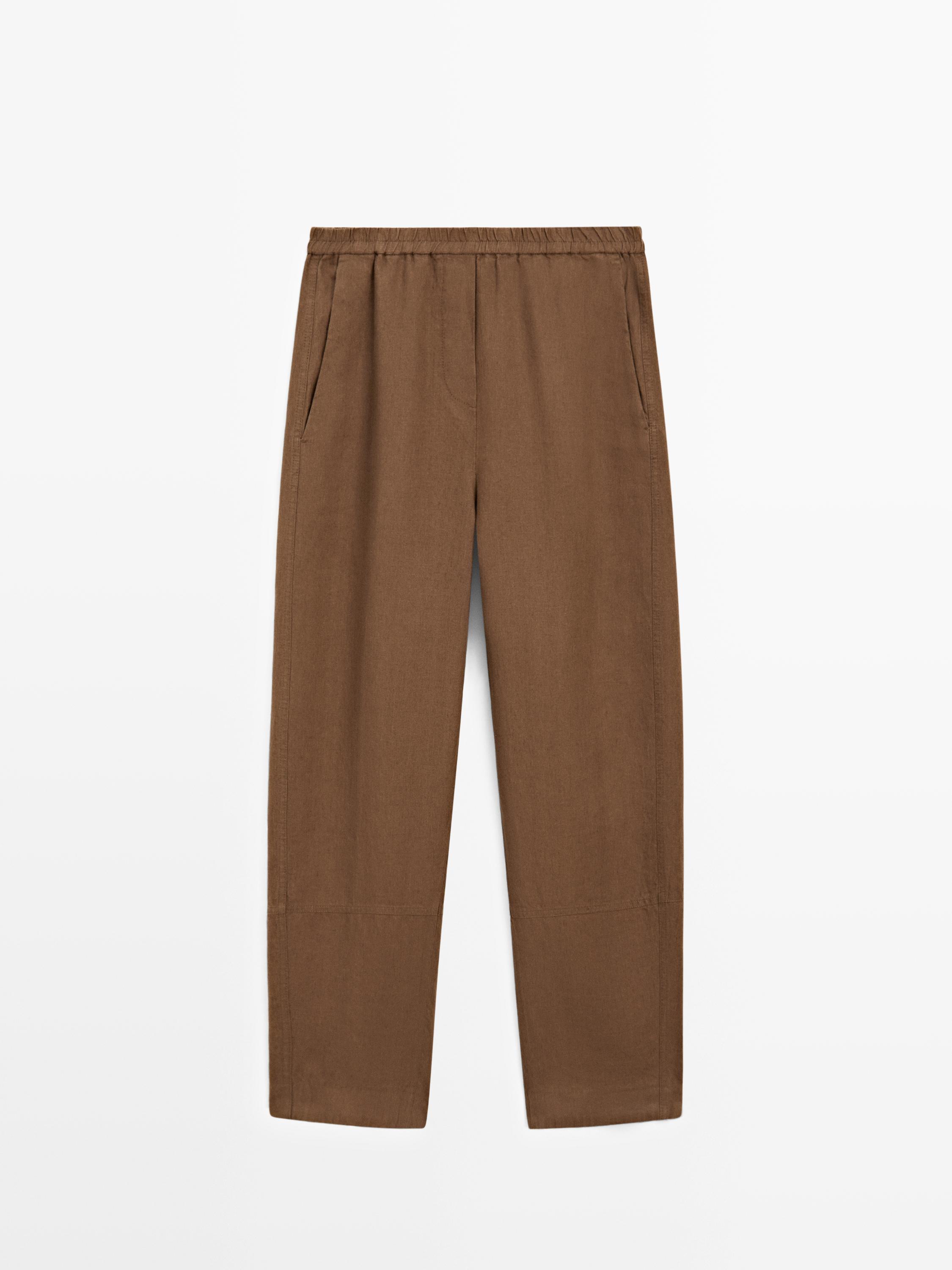 Vista frontal de pantalones cafés con cintura elástica y bolsillos laterales.