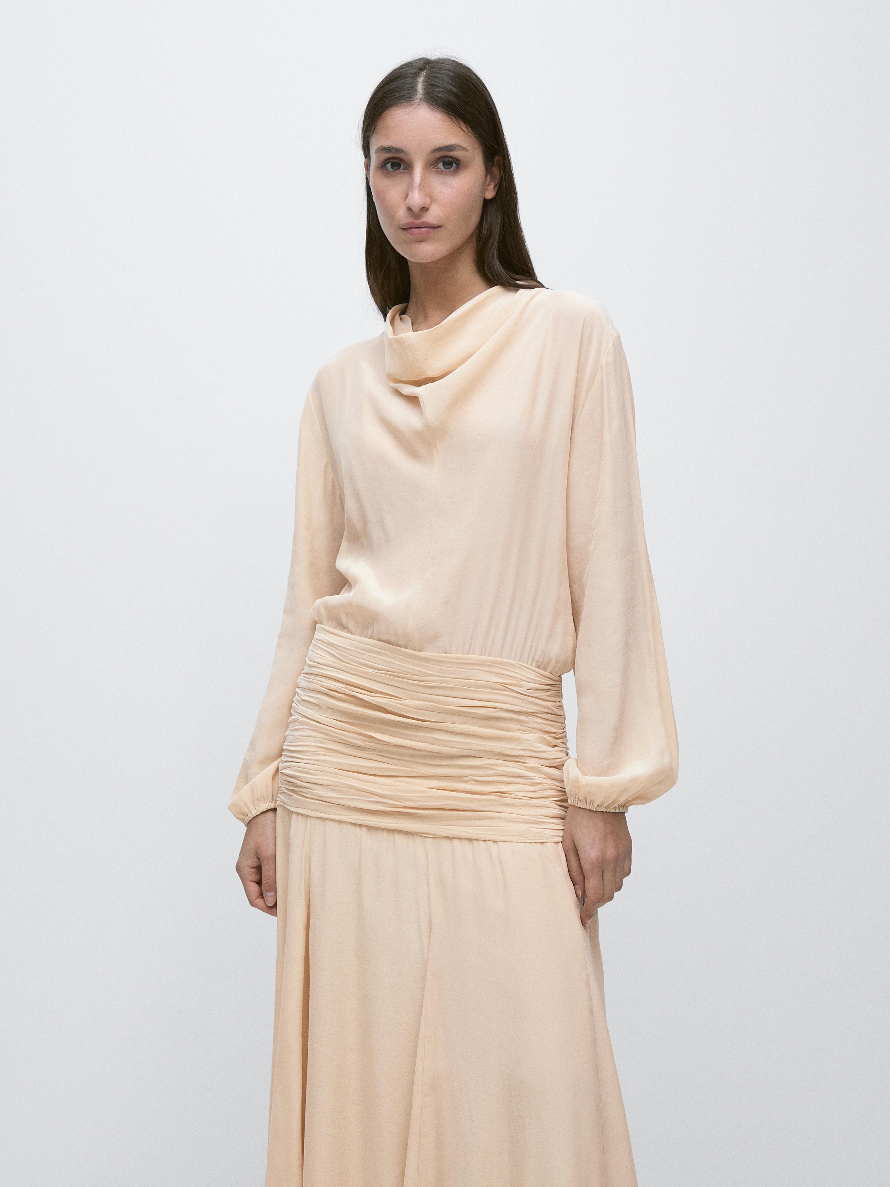 Plan moyen de robe longue fluide couleur avec détail de volant à la taille et manches longues.