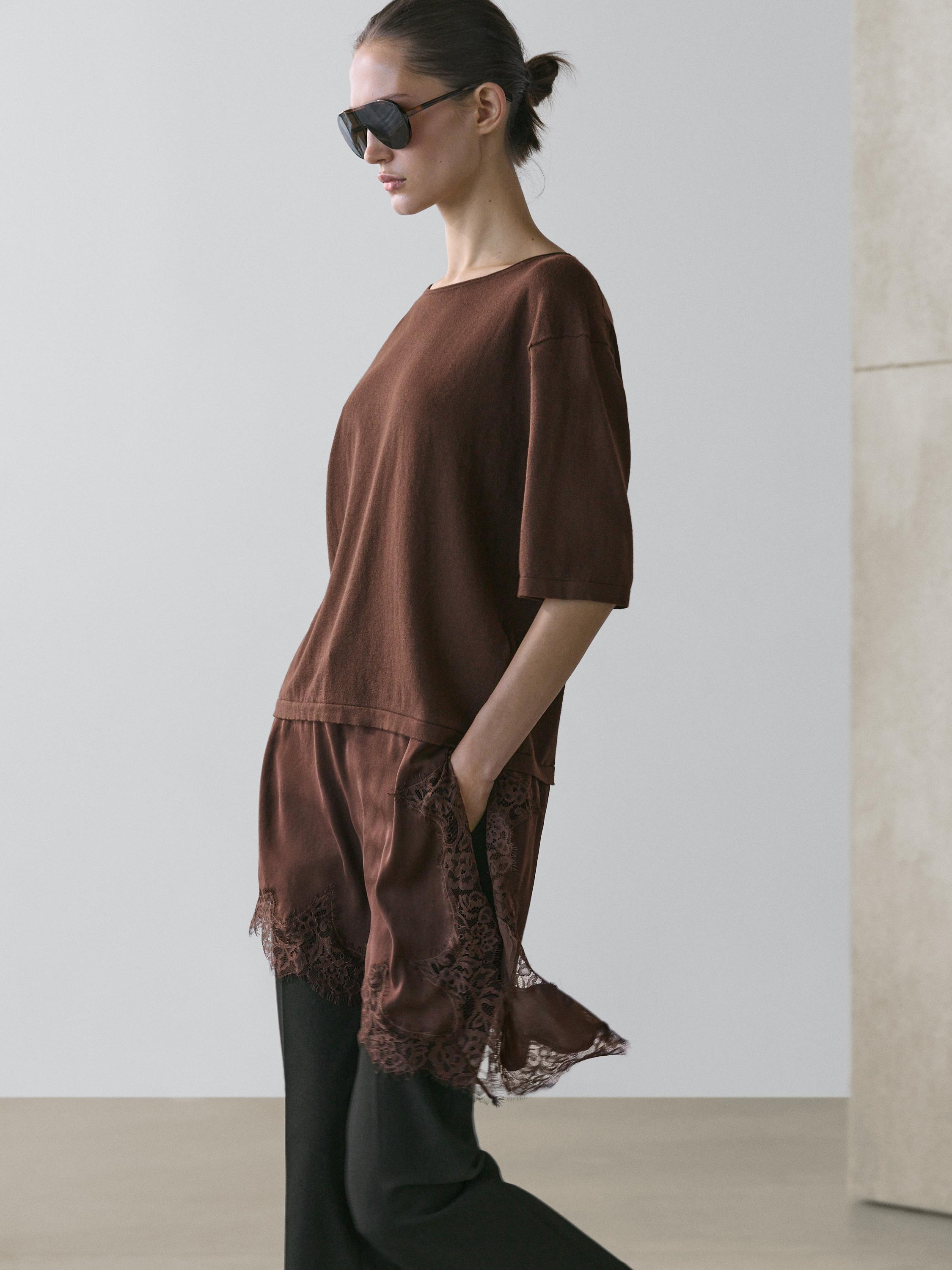 plaintext Medium shot of a brown dress with lace detail on the hem and side pocket, paired with black pants.