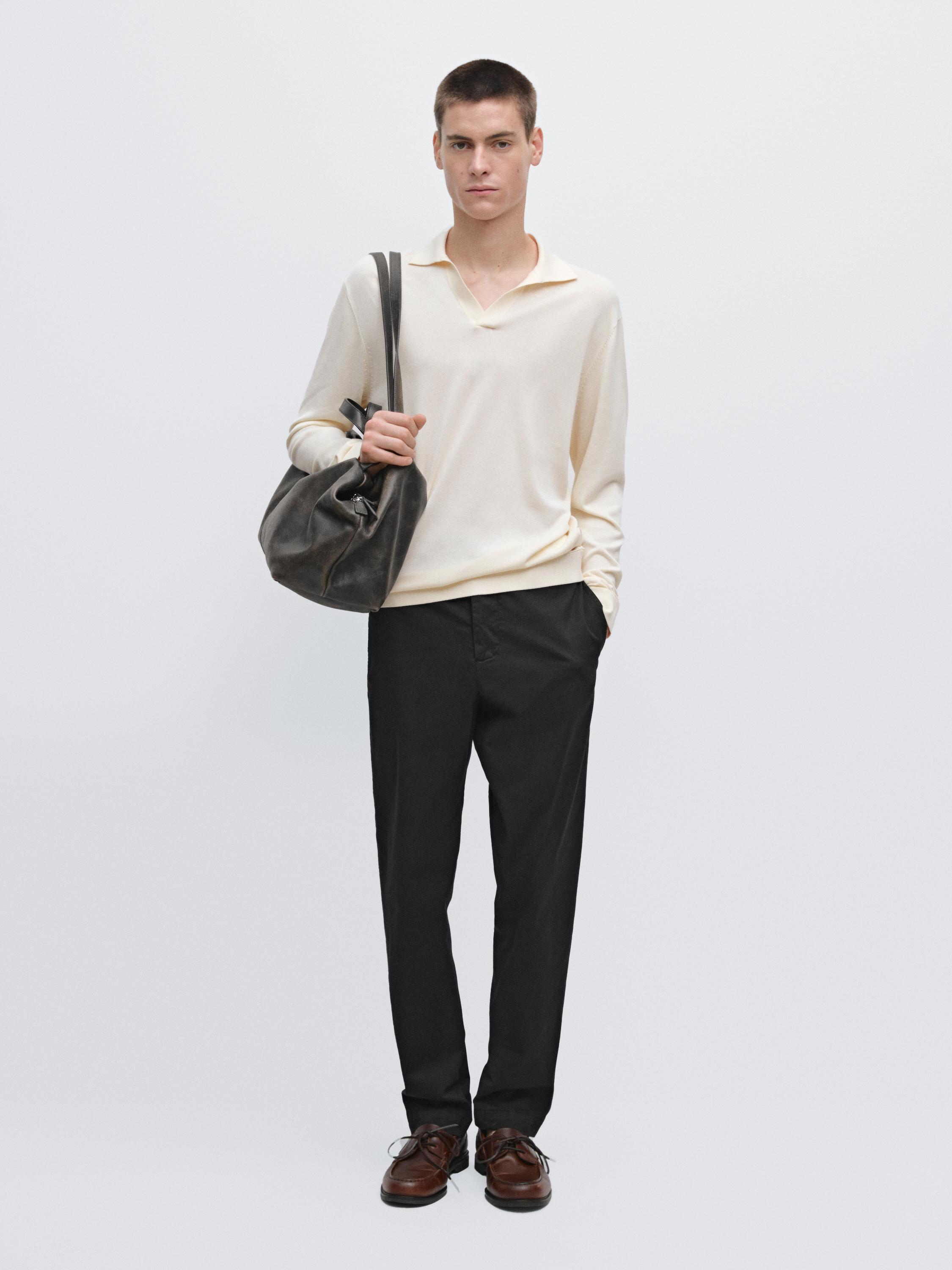 Slim-fit navy blue pants set and long-sleeve cream sweater with an open collar.