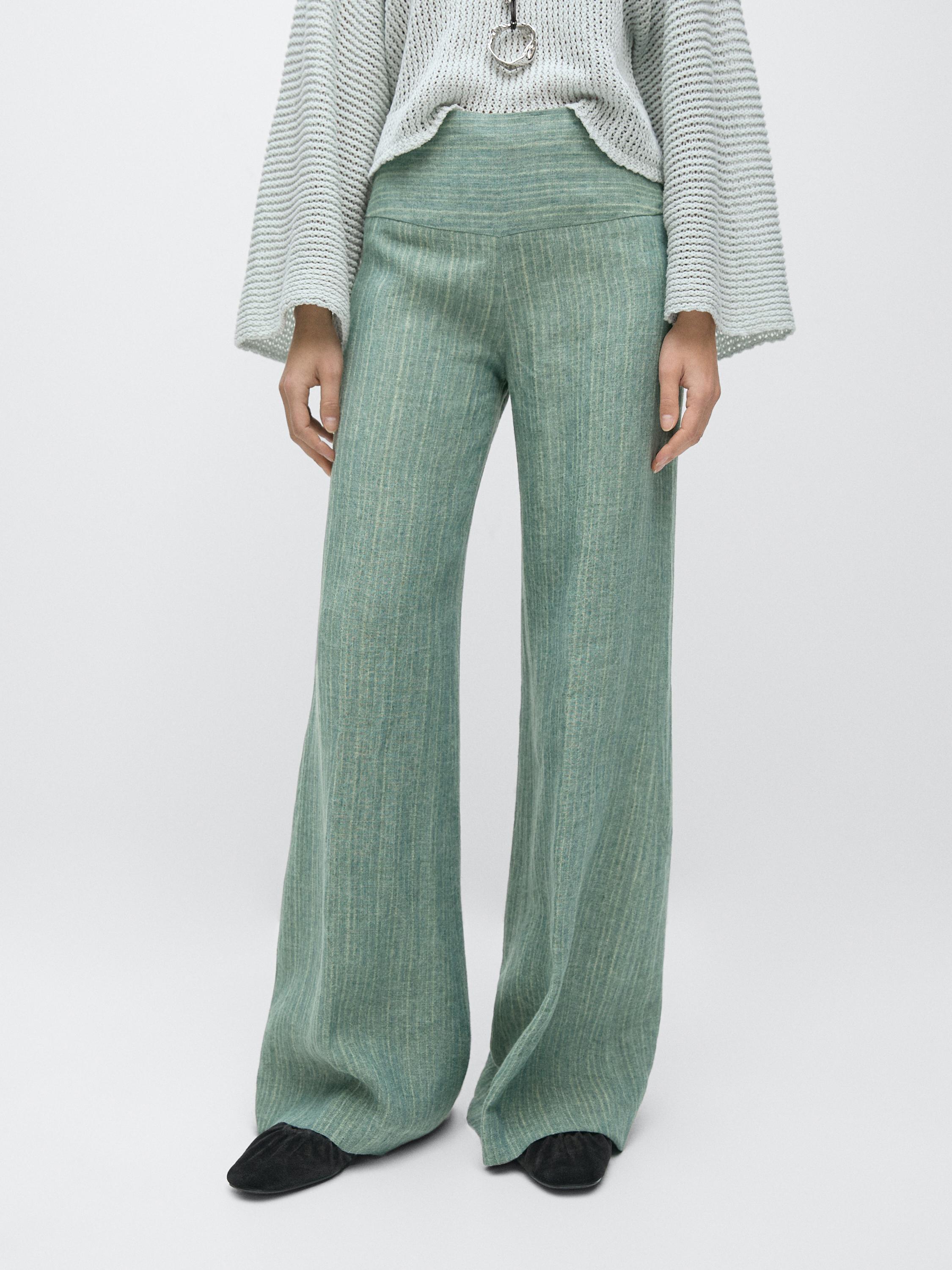 Conjunto de pantalón fluido verde agua con rayas y fajín, combinado con suéter de manga ancha.