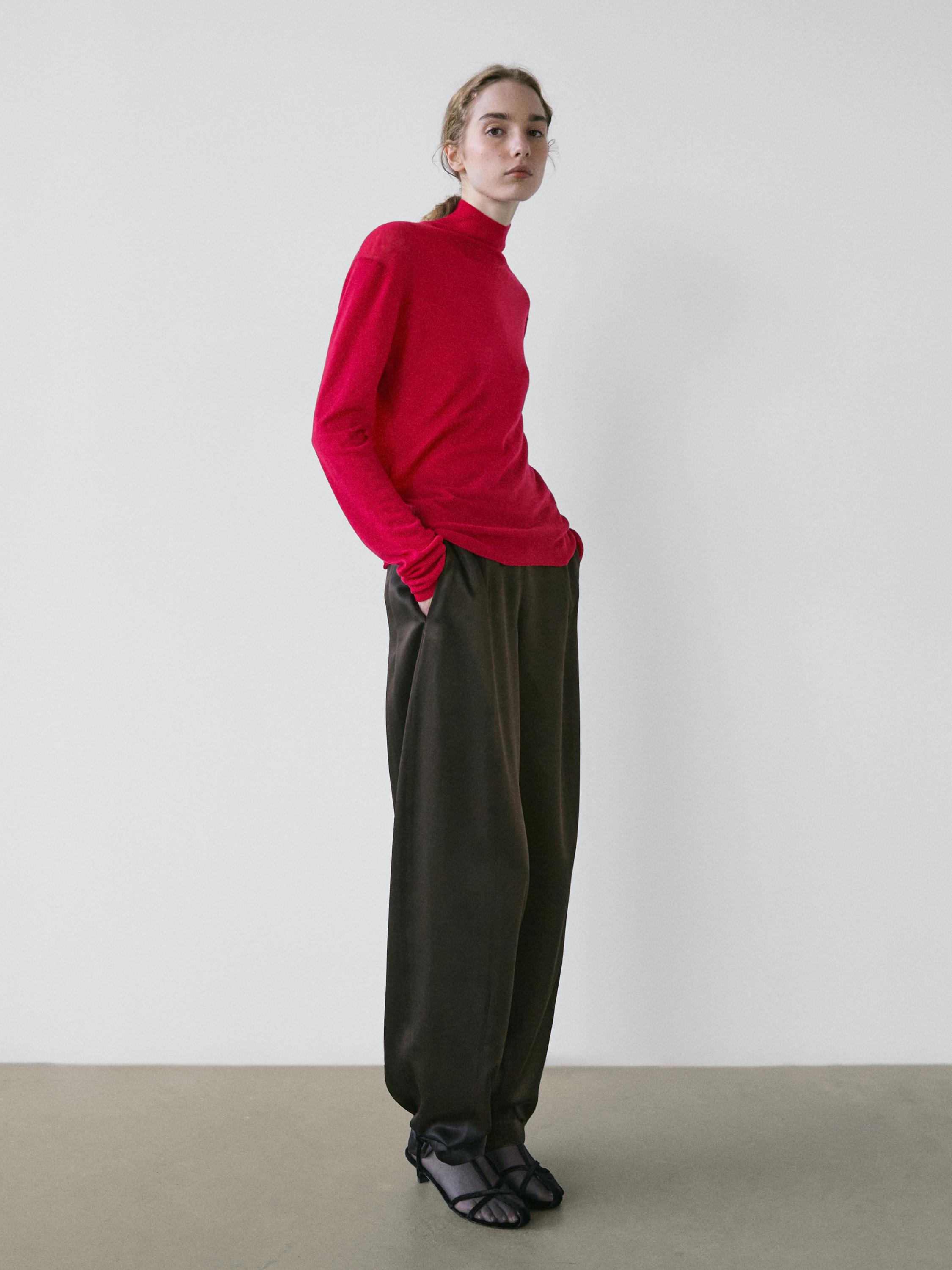 Set compus din pulover roșu rubiniu cu guler perkins și pantaloni largi închiși la culoare, cu sandale negre.