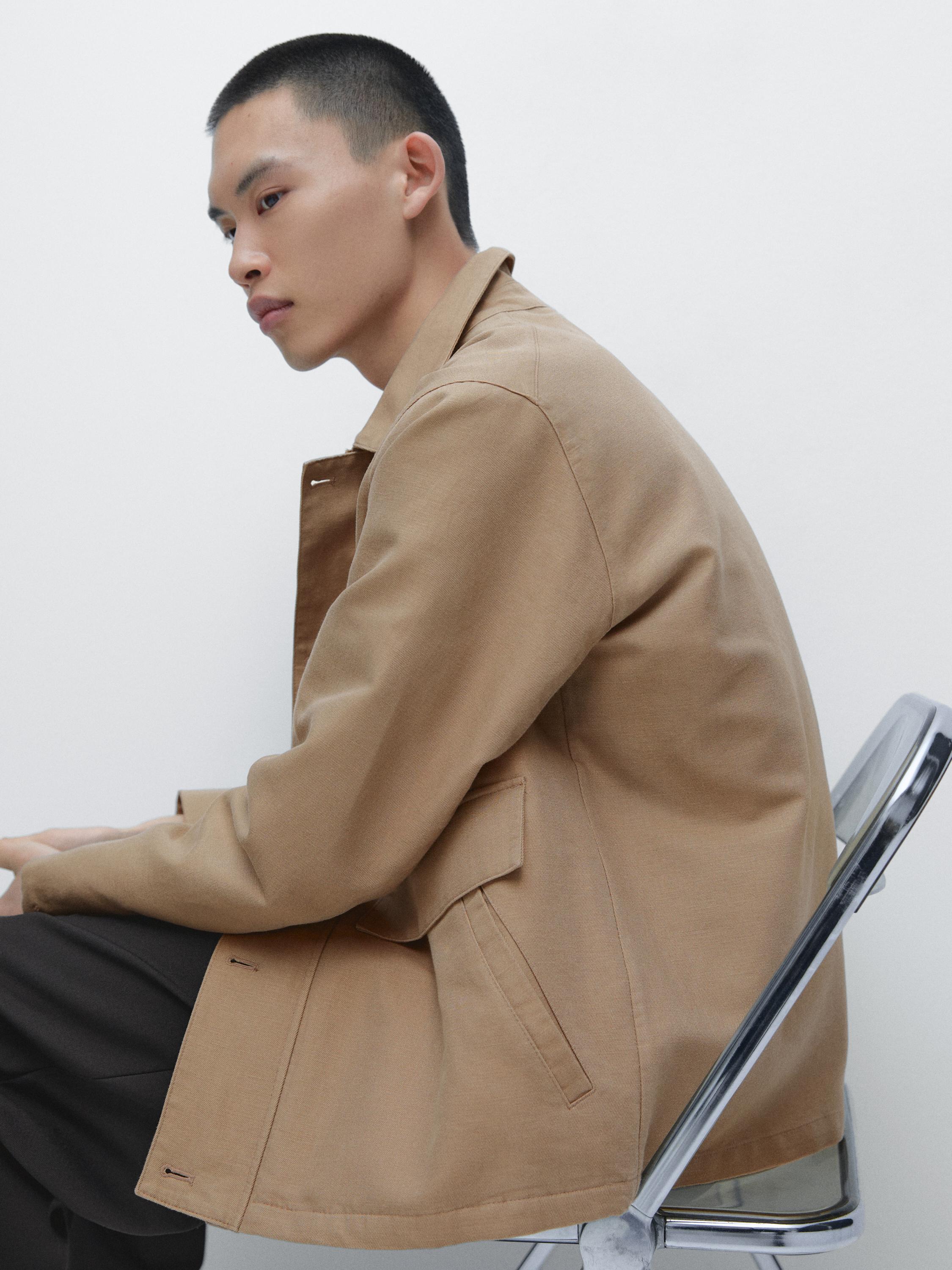 Middellange opname van een beige jas met zijzakken en revers.