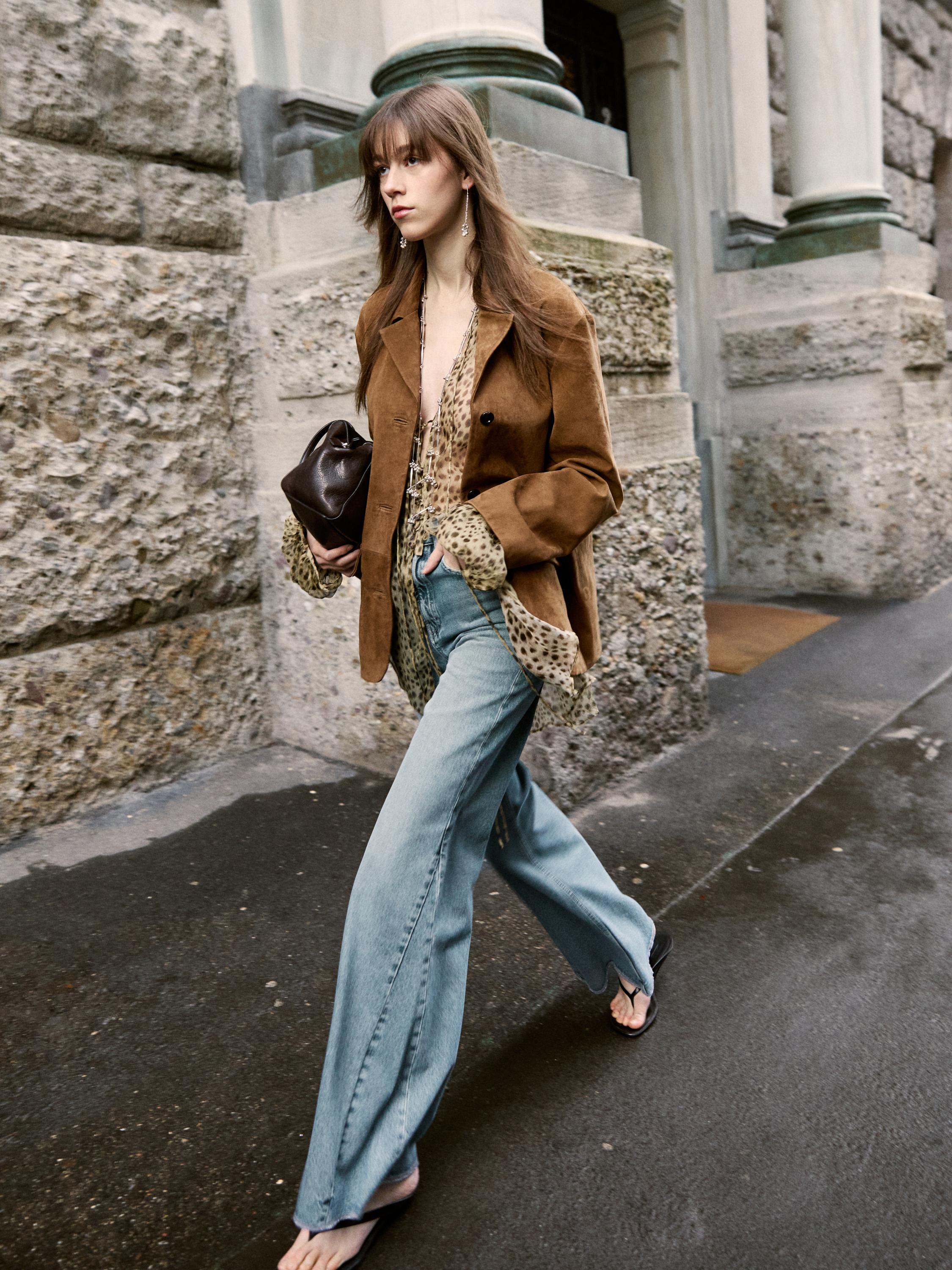 Ensemble composé d'une veste marron, d'un chemisier imprimé léopard, d'un jean large bleu et de sandales noires.