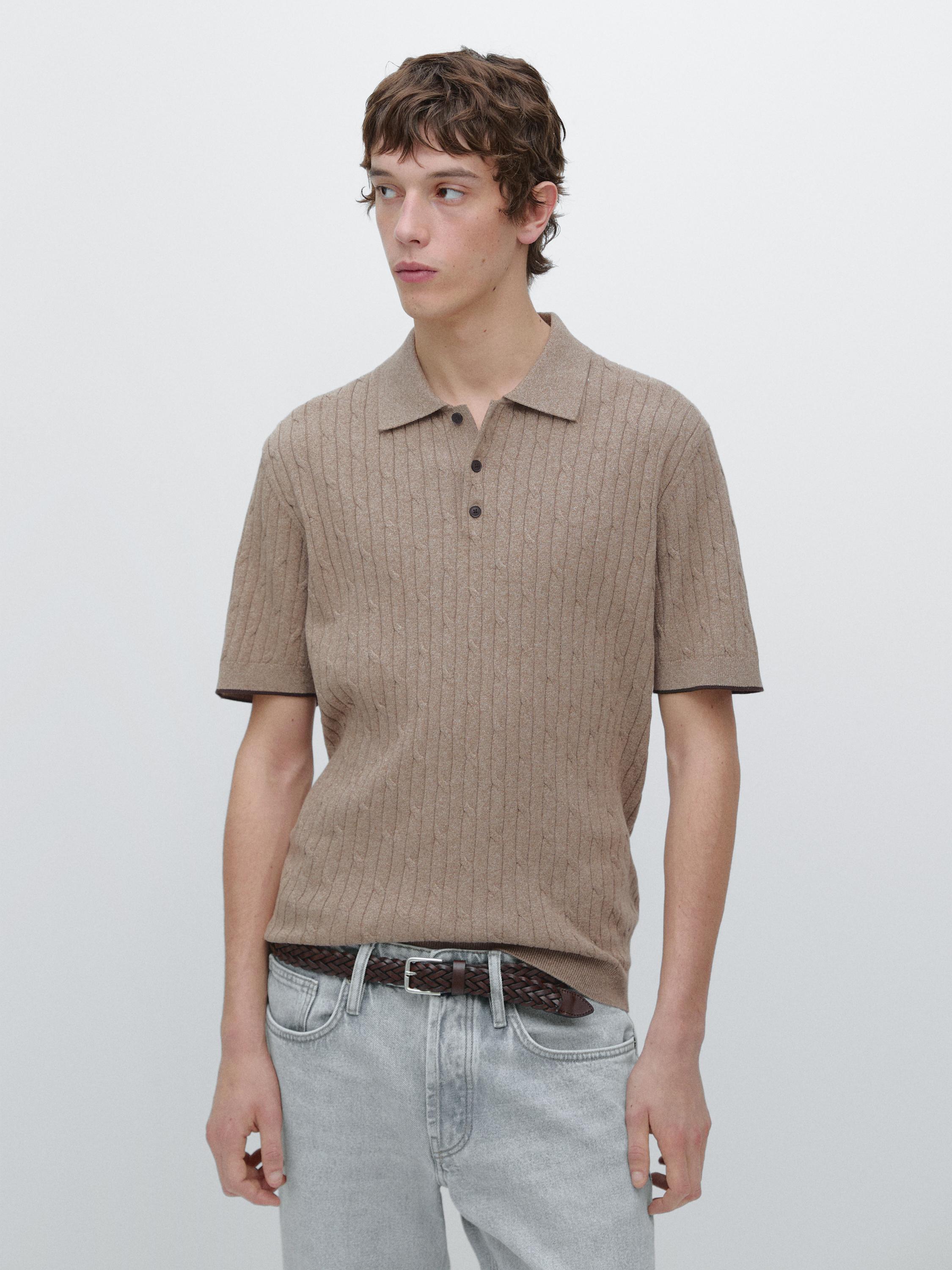 Ensemble de polo beige texturé côtelé, à manches courtes et boutons foncés, assorti d'un jean clair et d'une ceinture tressée.