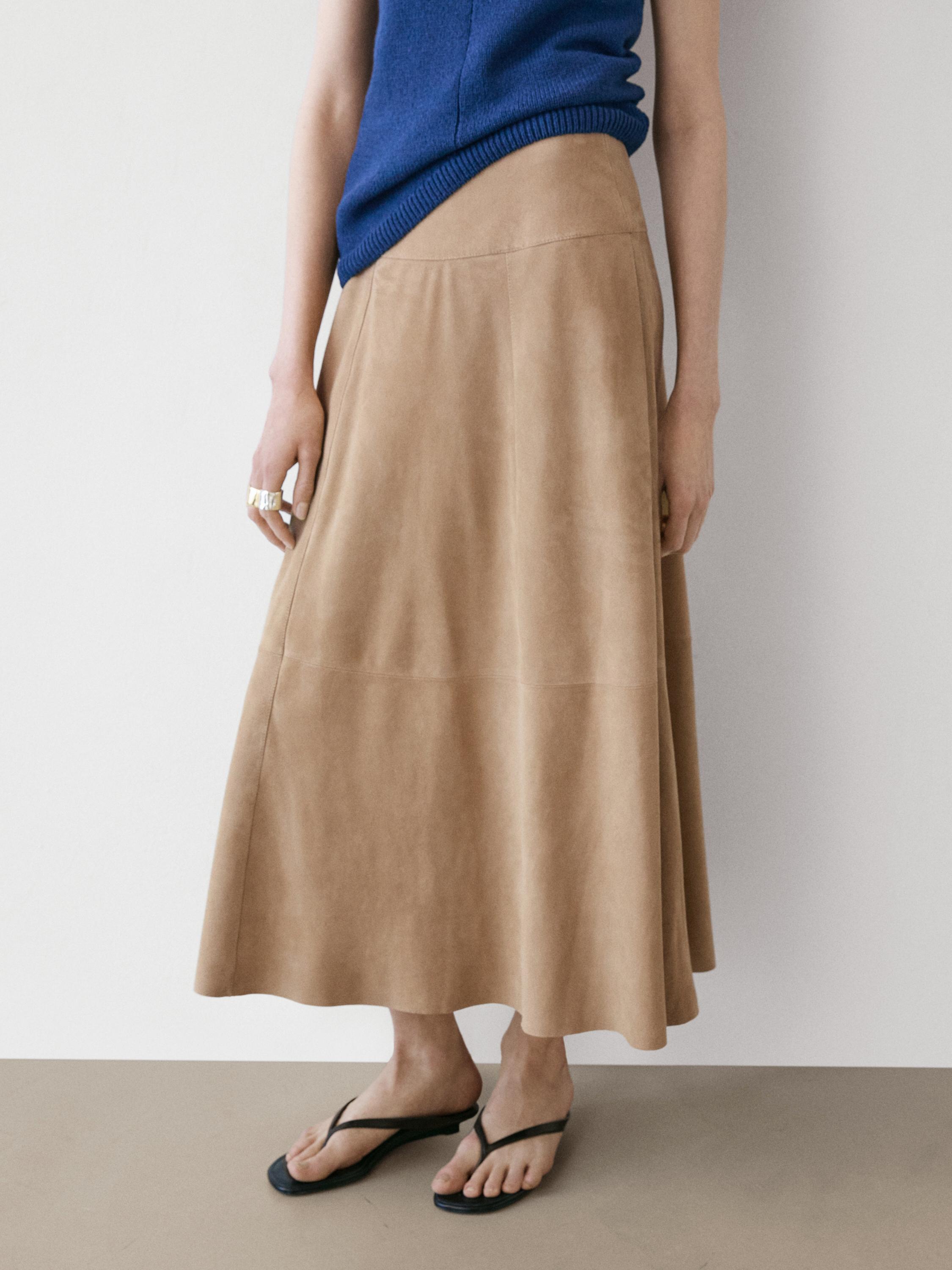 Conxunto de saia longa cor area con faixa e sandalias negras.