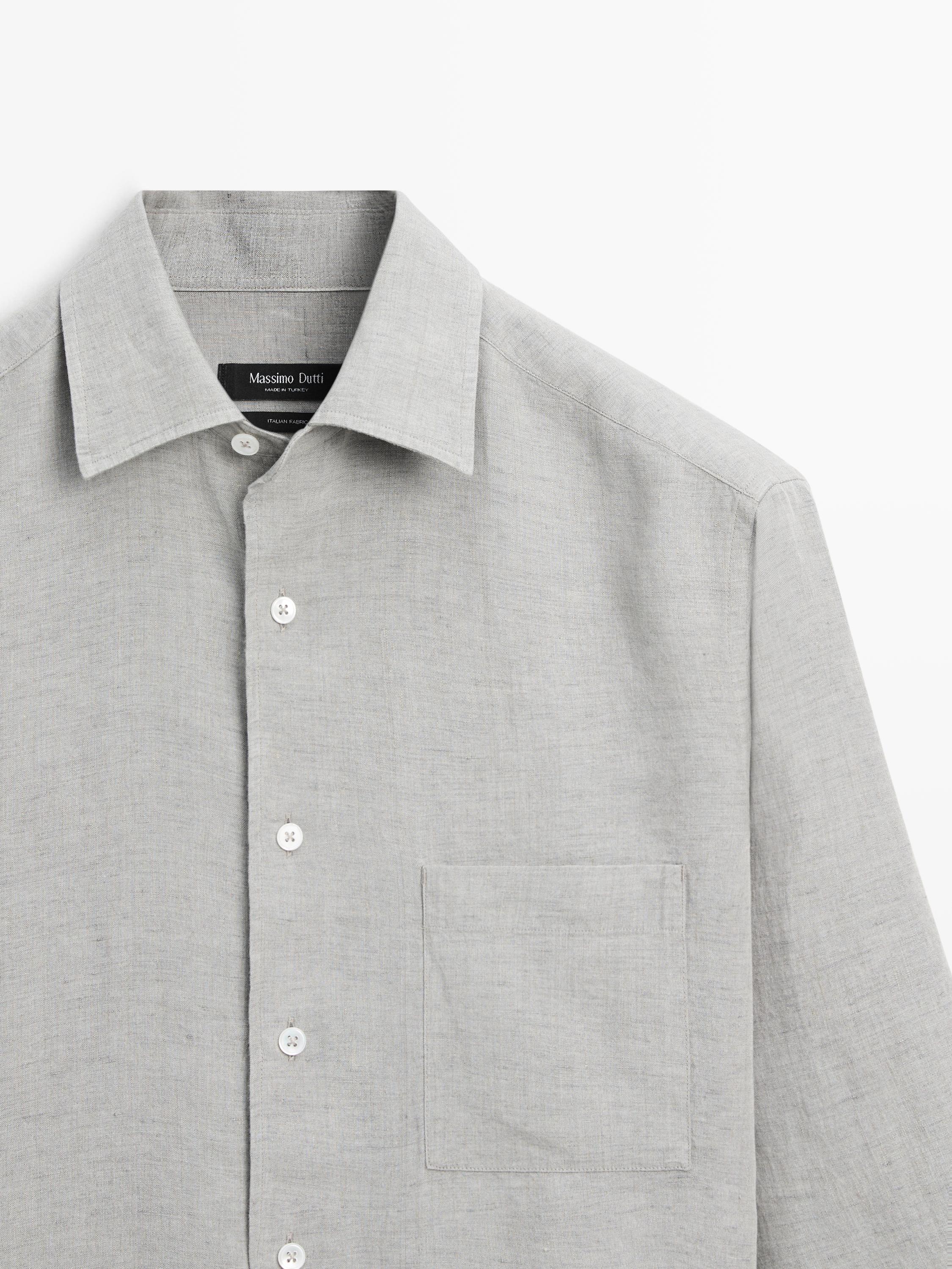 Κοντινό πλάνο γκρι μακρυμάνικου πουκαμίσου με κλασικό γιακά, κουμπιά μπροστά και τσέπη στο στήθος.