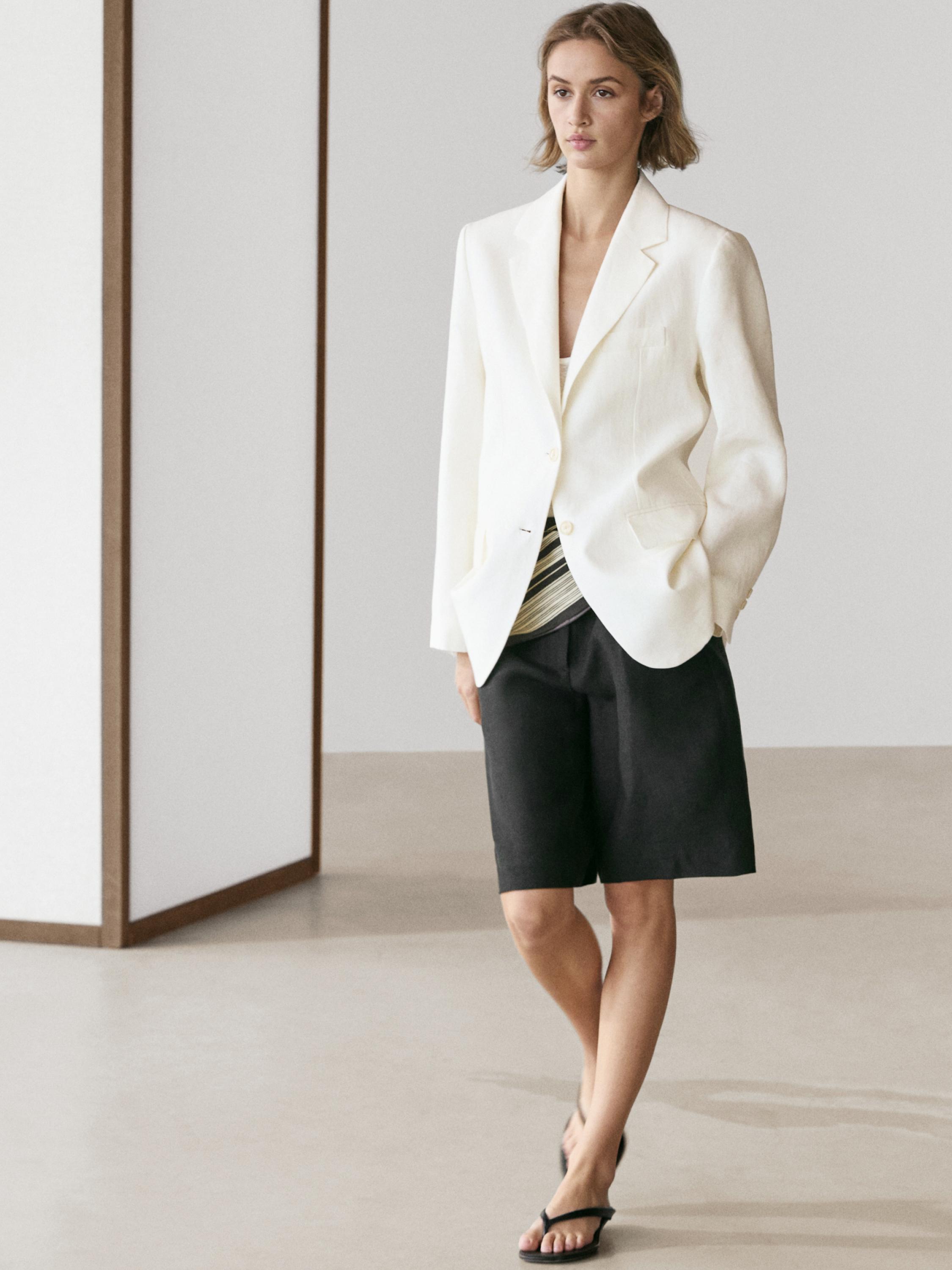 Conjunt de bermuda negra llarga i blazer blanc amb butxaques laterals.