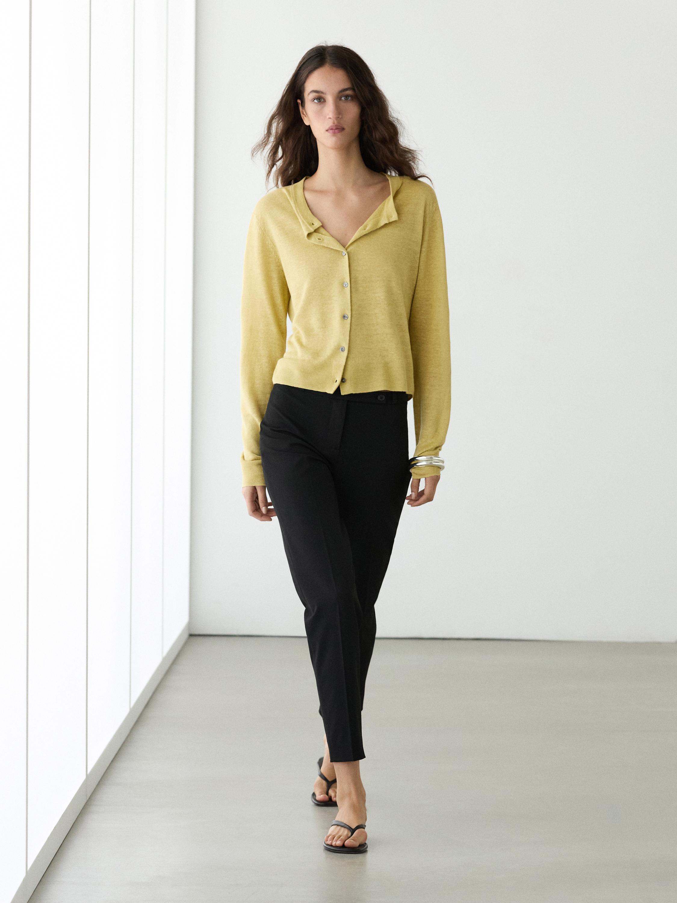 Düğmeli lime hırka ve dar siyah pantolon takımı.