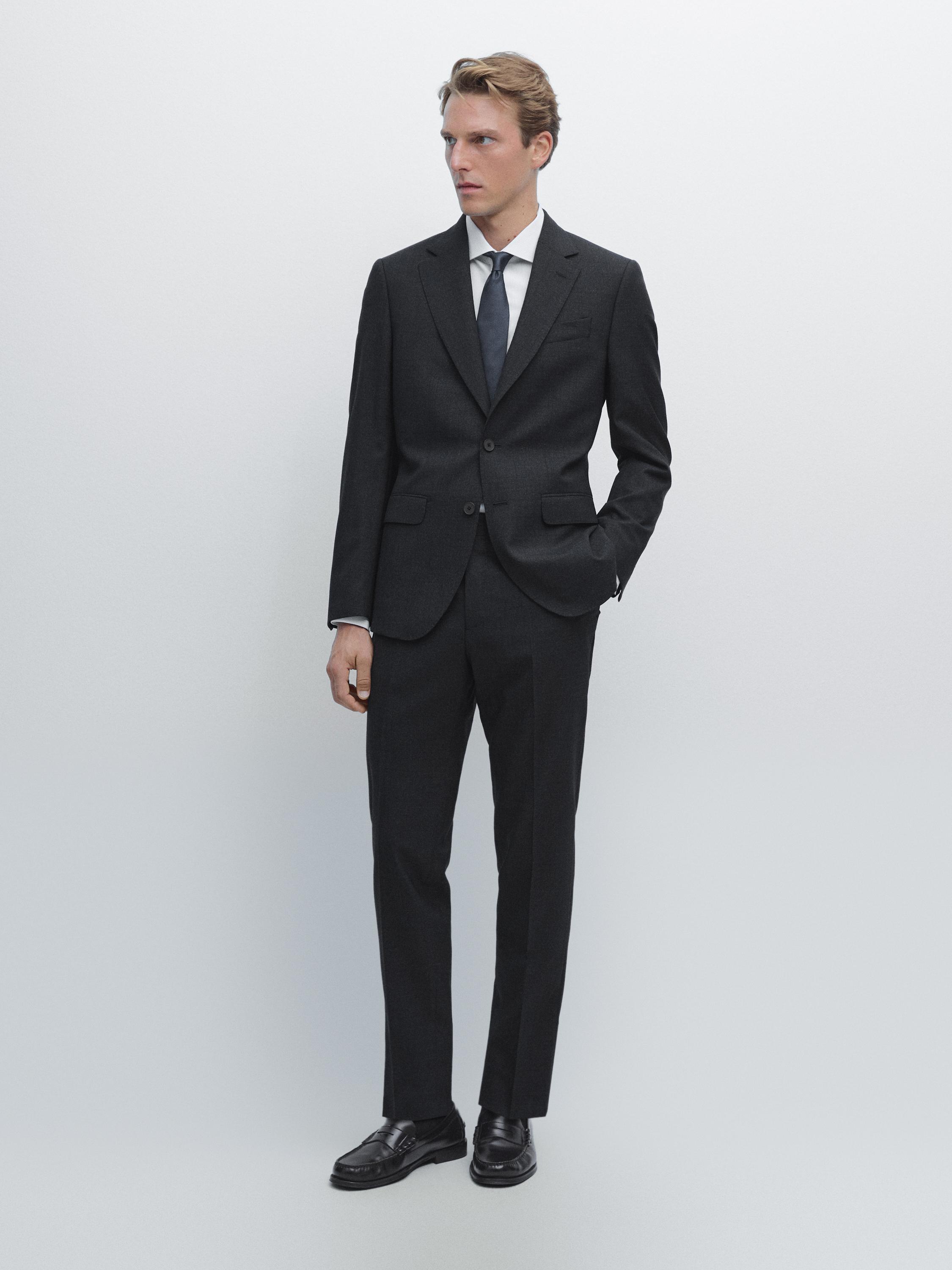 Ensemble de costume bleu marine avec veste à deux boutons et pantalon de costume. Chemise blanche et cravate bleue.