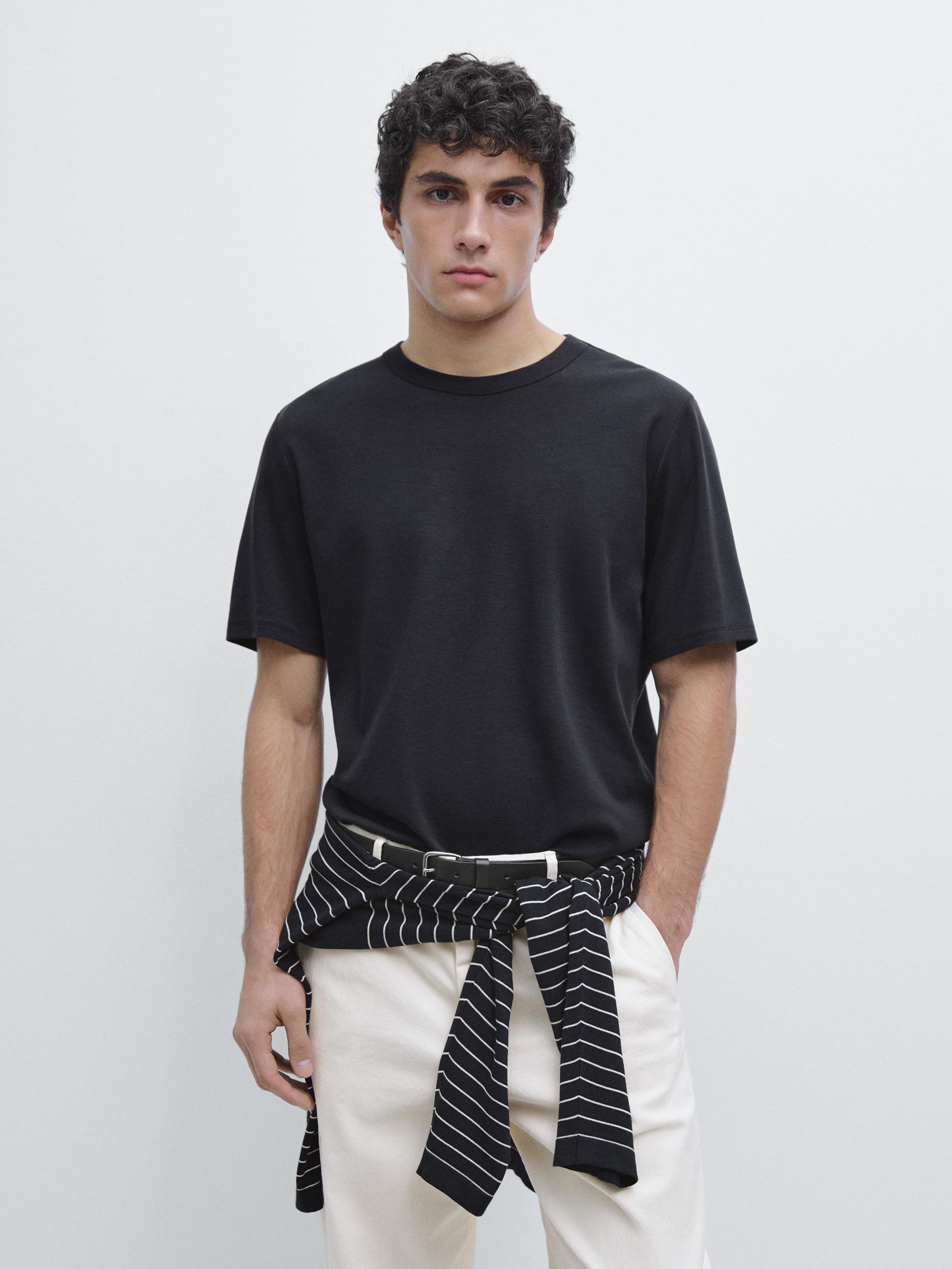 Set aus marineblauem Kurzarm-T-Shirt und weißer Hose, mit einem schwarz gestreiften Pullover um die Taille gebunden.