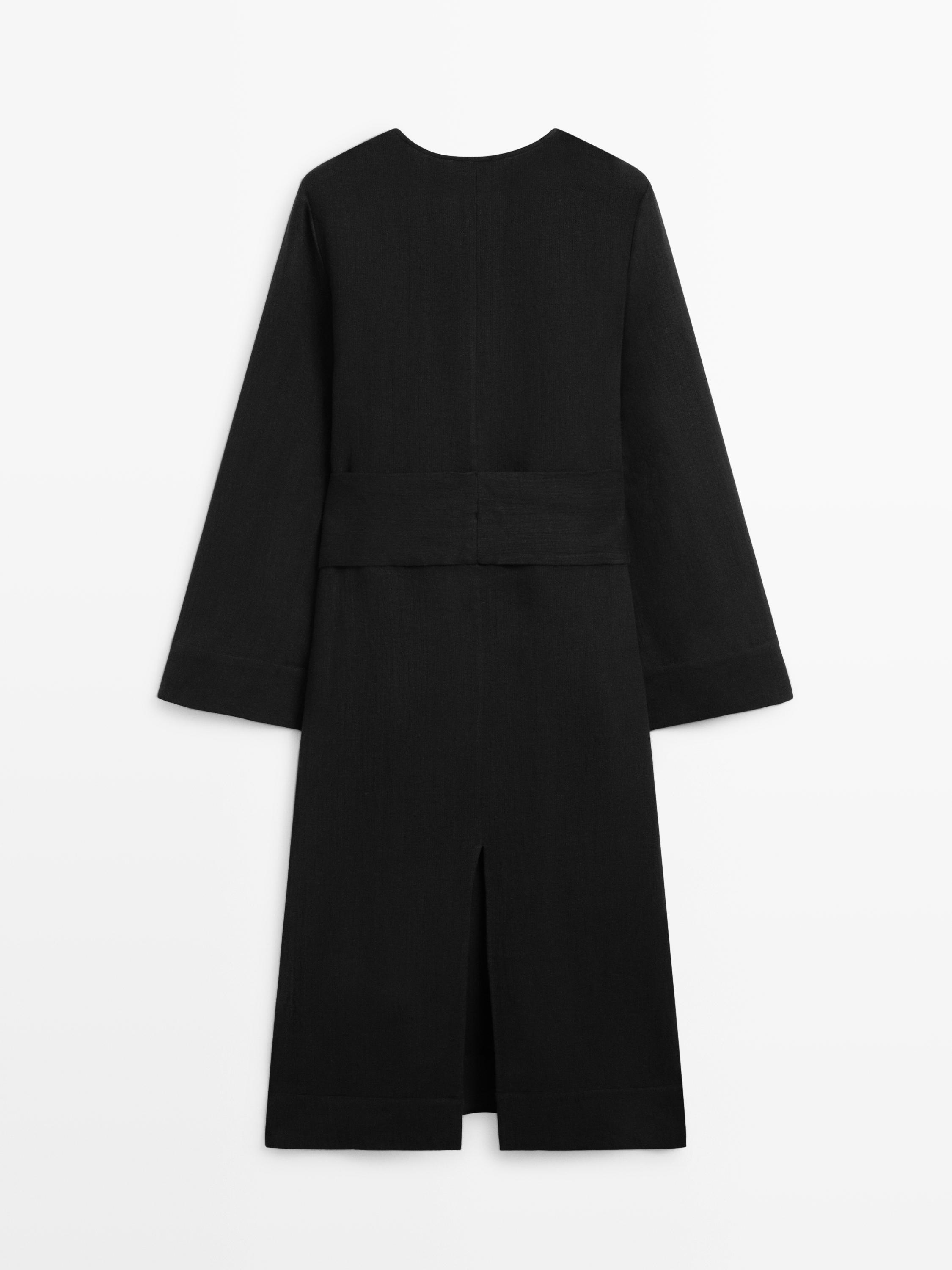 Vue arrière d'une robe noire à manches longues avec une fente en bas du dos.