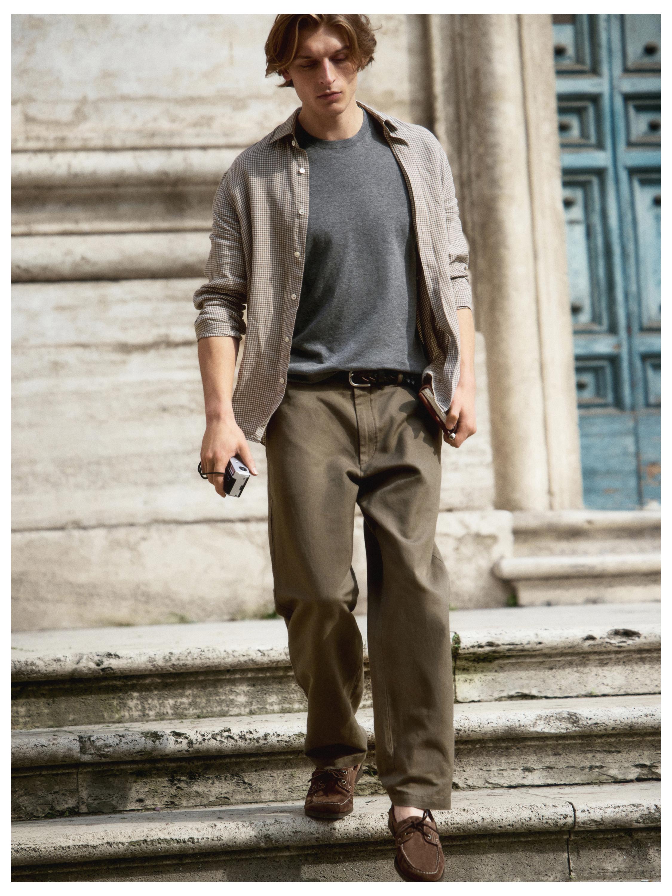 Conjunto de camisa a cuadros beige, camiseta gris, pantalones caqui con bolsillos laterales y mocasines marrones.