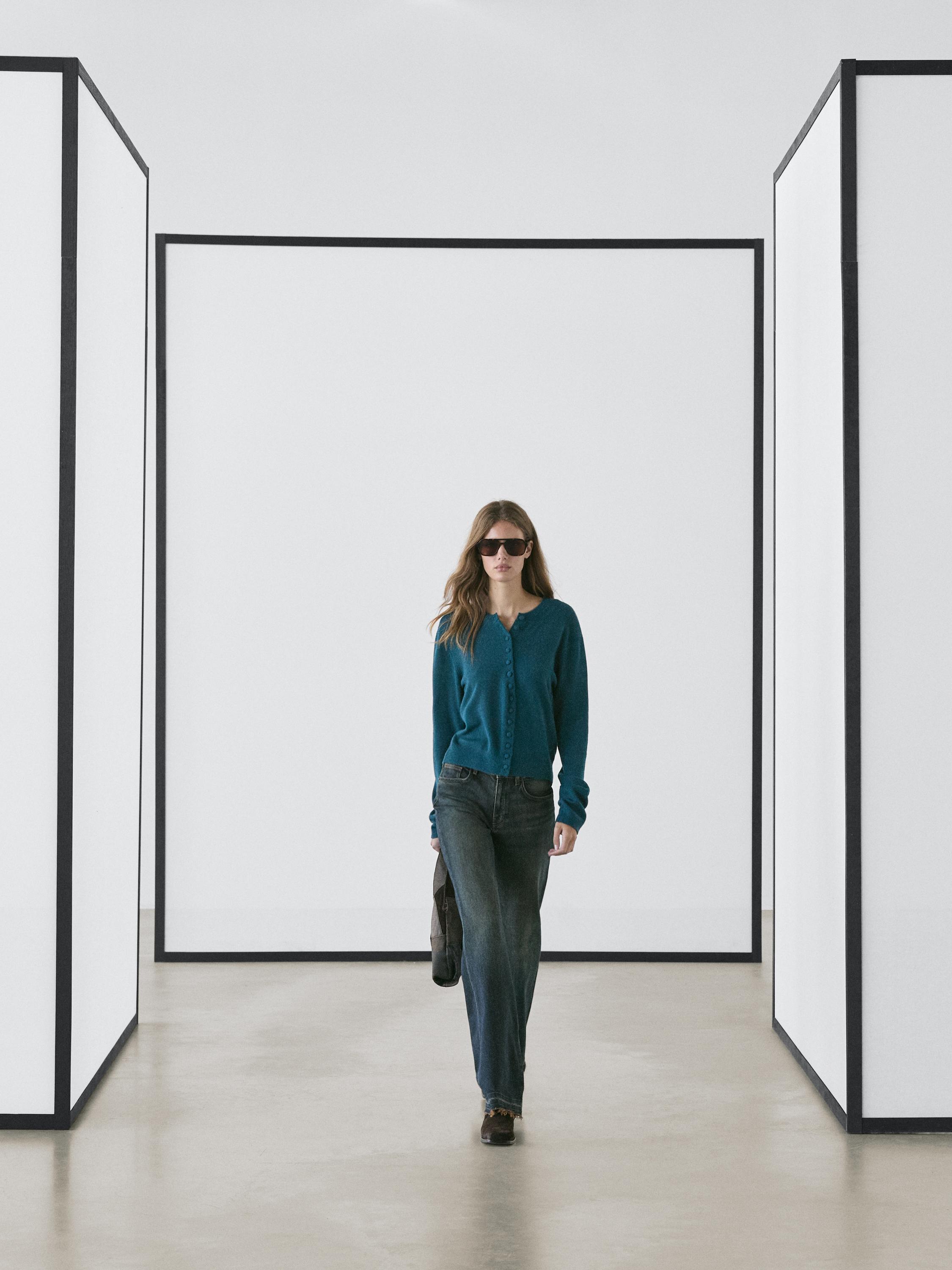 Conjunto de cardigán azul con botones forrados y jeans rectos oscuros.