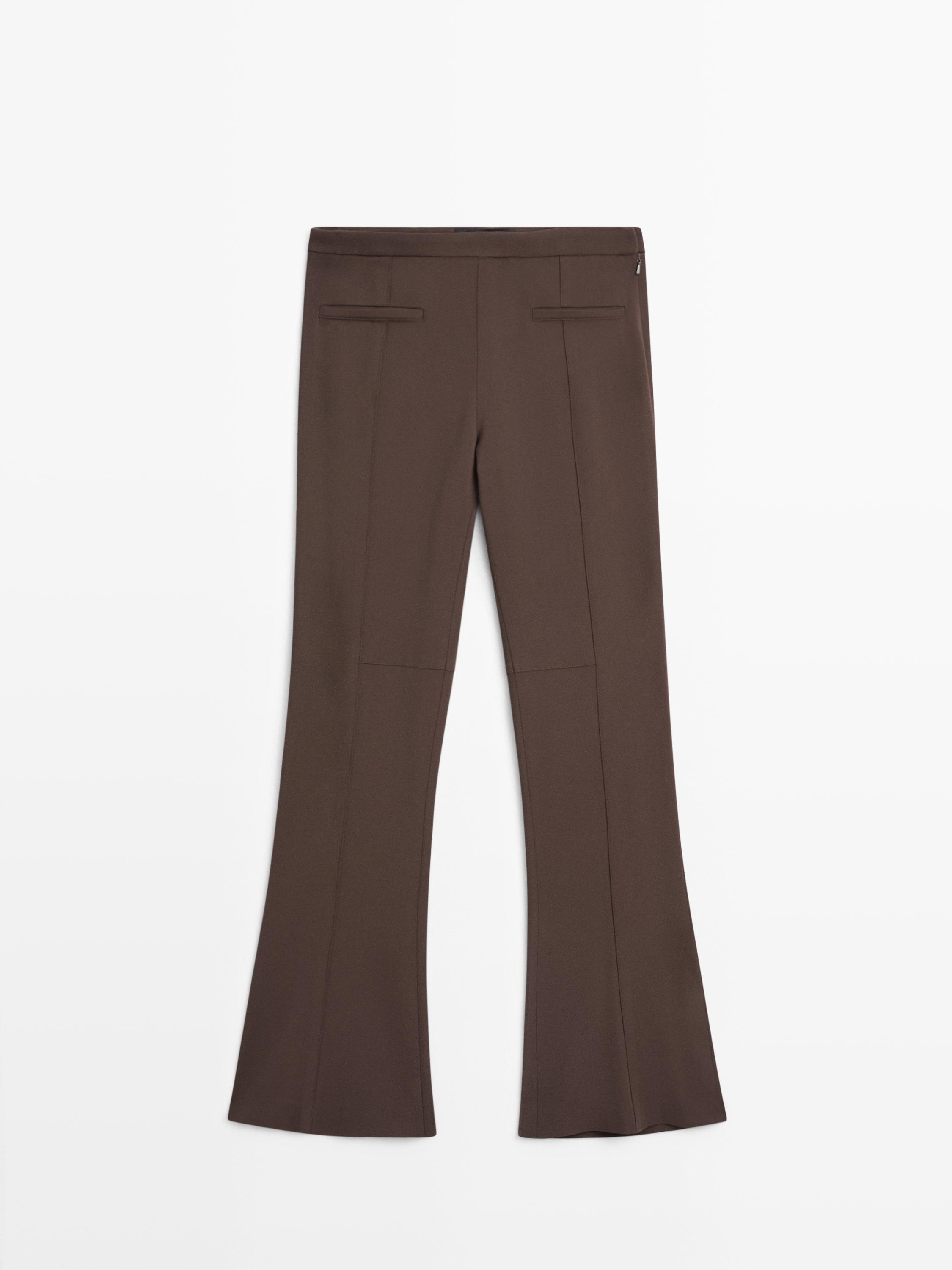 Back view of brown flare fit pants with decorative back pockets and visible seams.