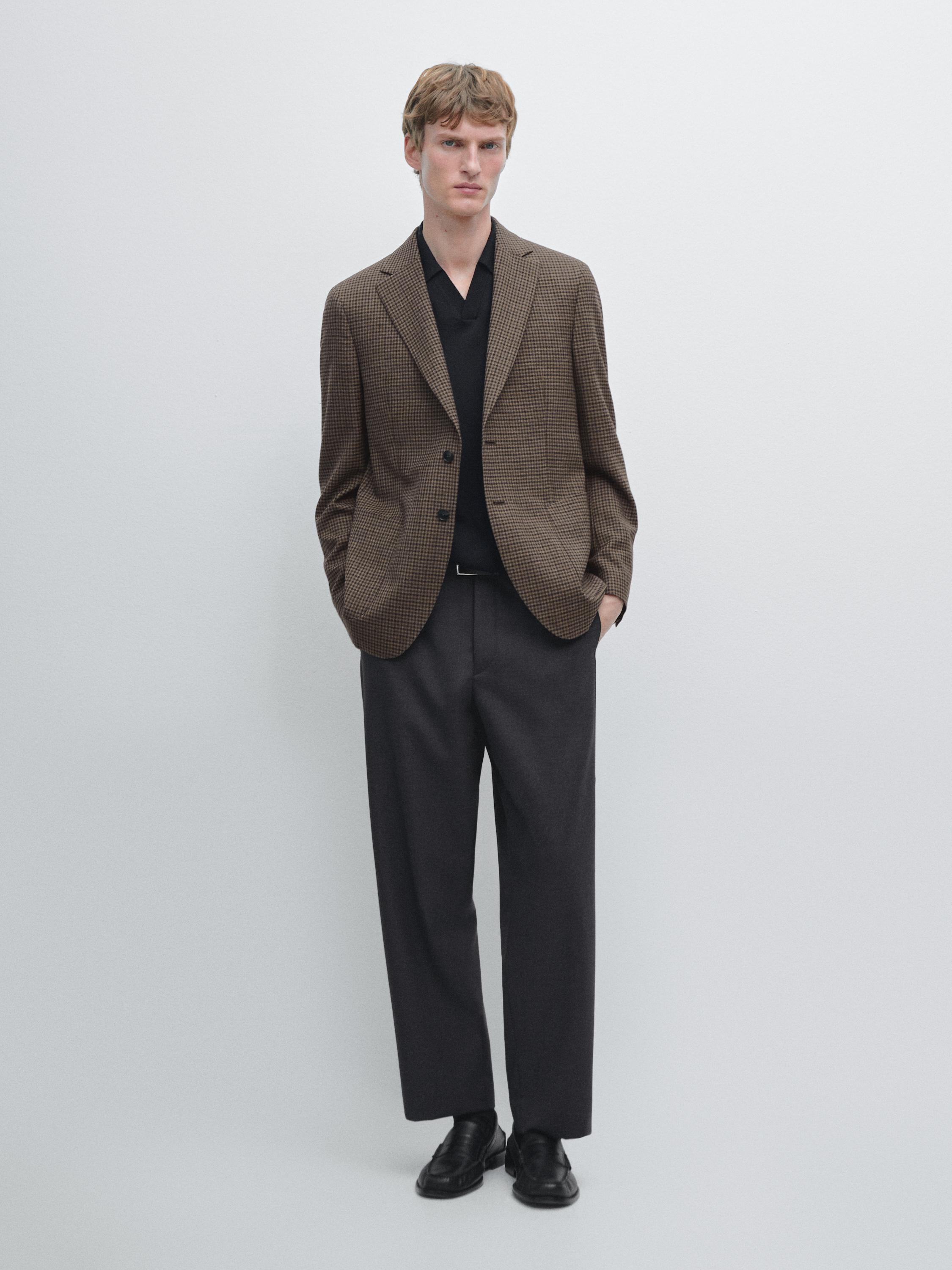 Set blazer cokelat dengan saku samping, kemeja hitam, dan celana panjang lebar abu-abu.