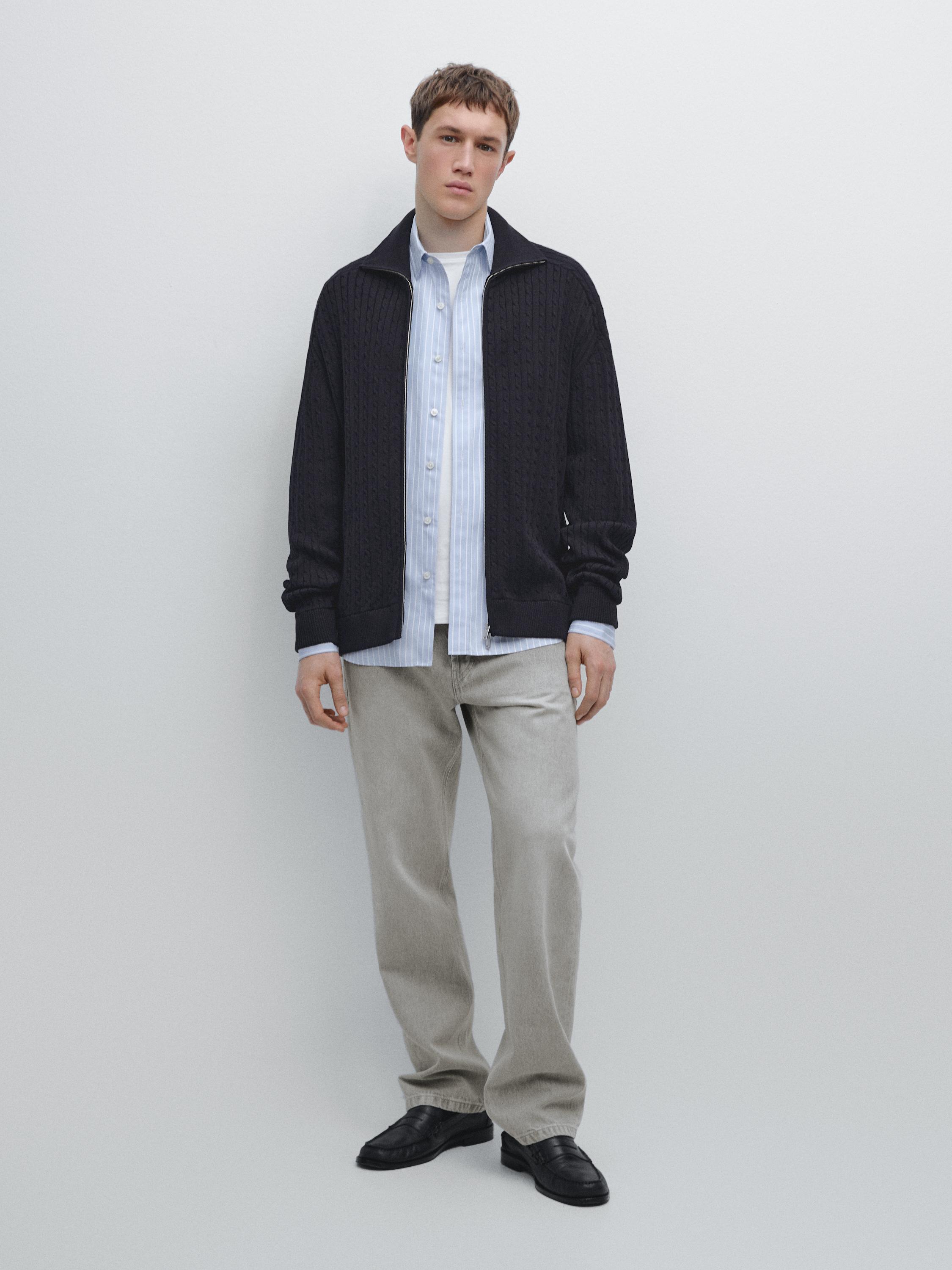 Fermuarlı lacivert hırka, açık mavi çizgili gömlek ve düz bej pantolon takımı.