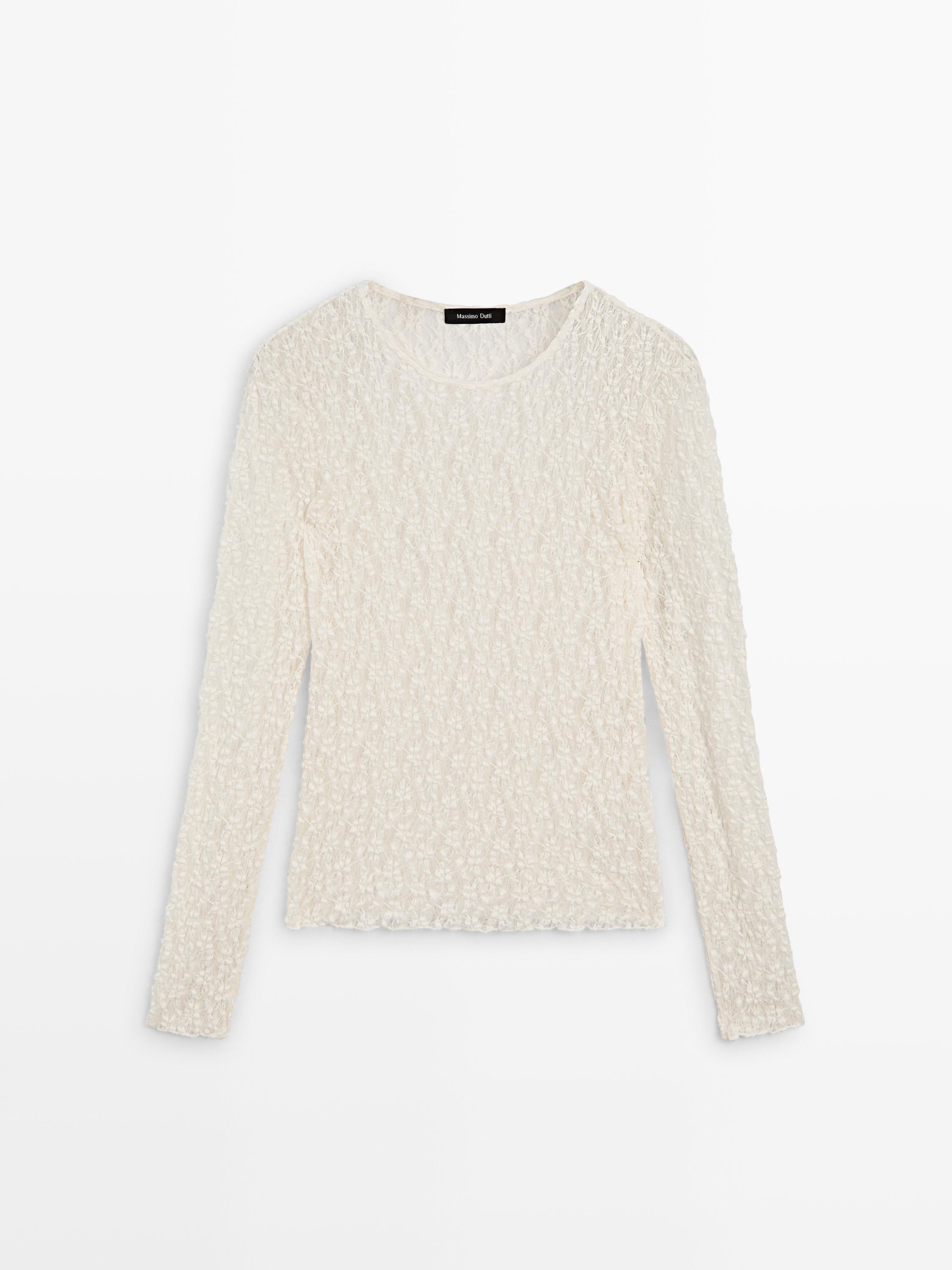Front view of a long-sleeve ecru top with an openwork design and a round neck.