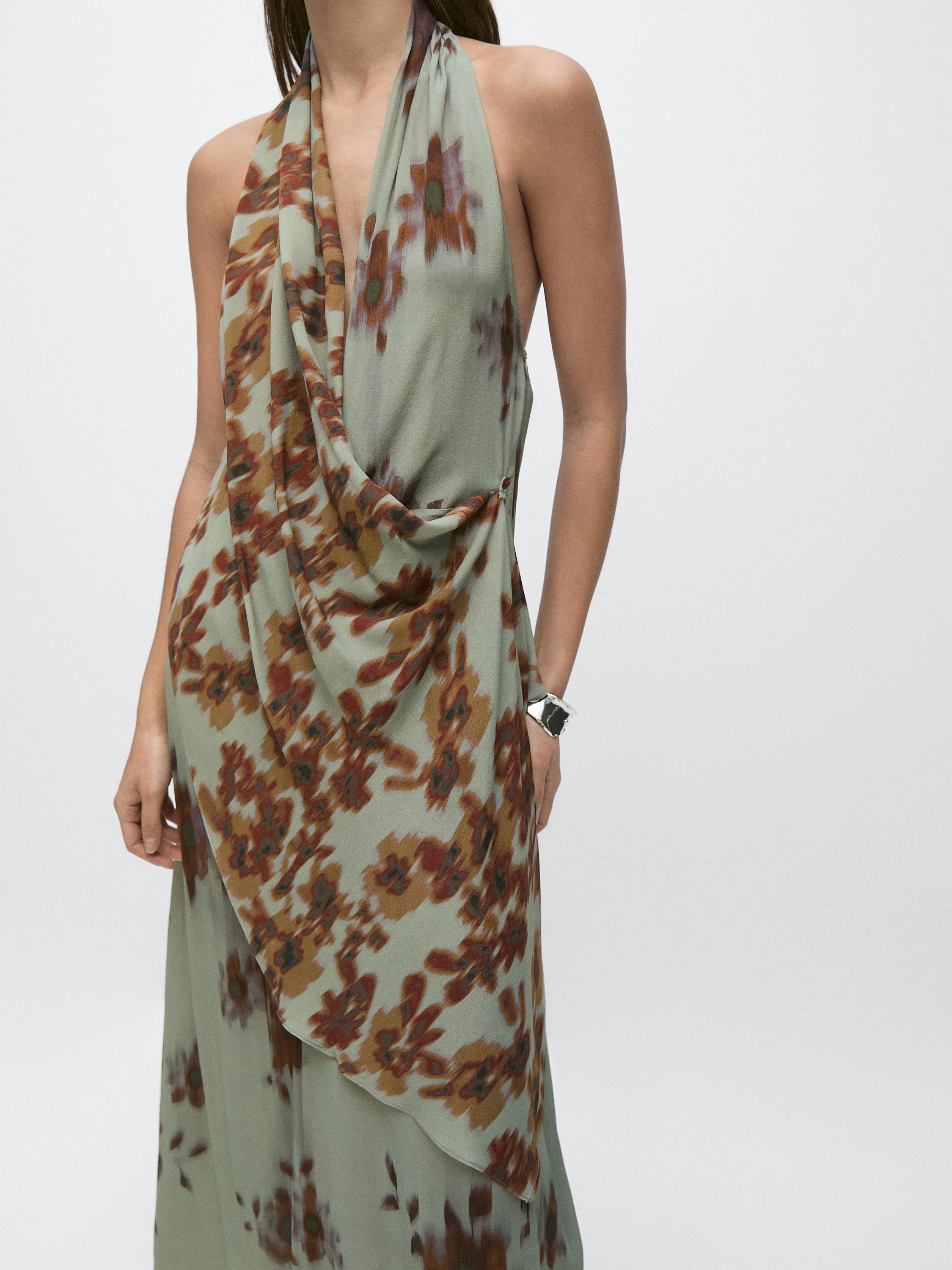 Medium shot of a teal halter mini dress with a brown floral print and front draping.