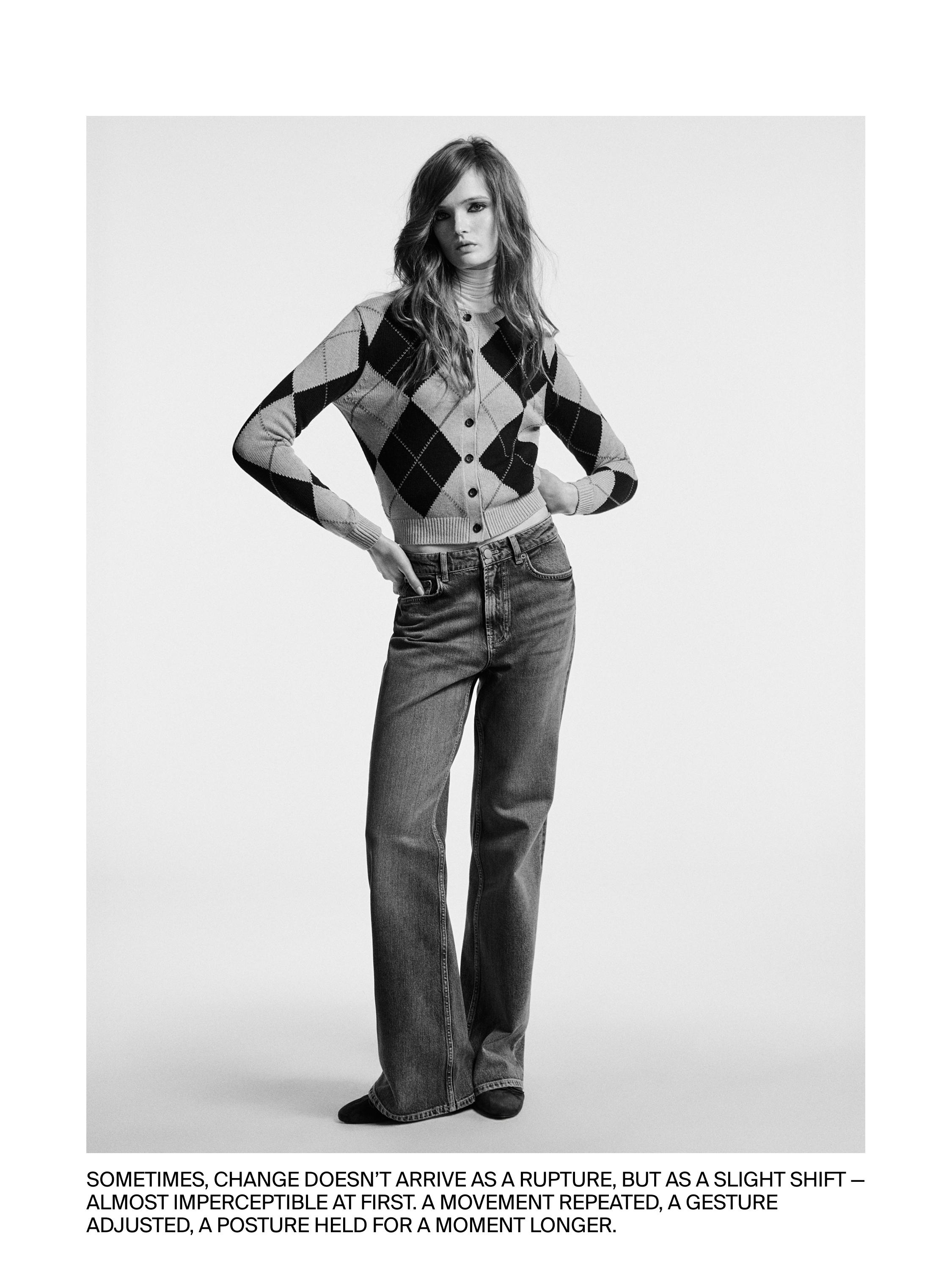 Megztas kardiganas su rombais ir sagomis bei tiesaus kirpimo džinsai.