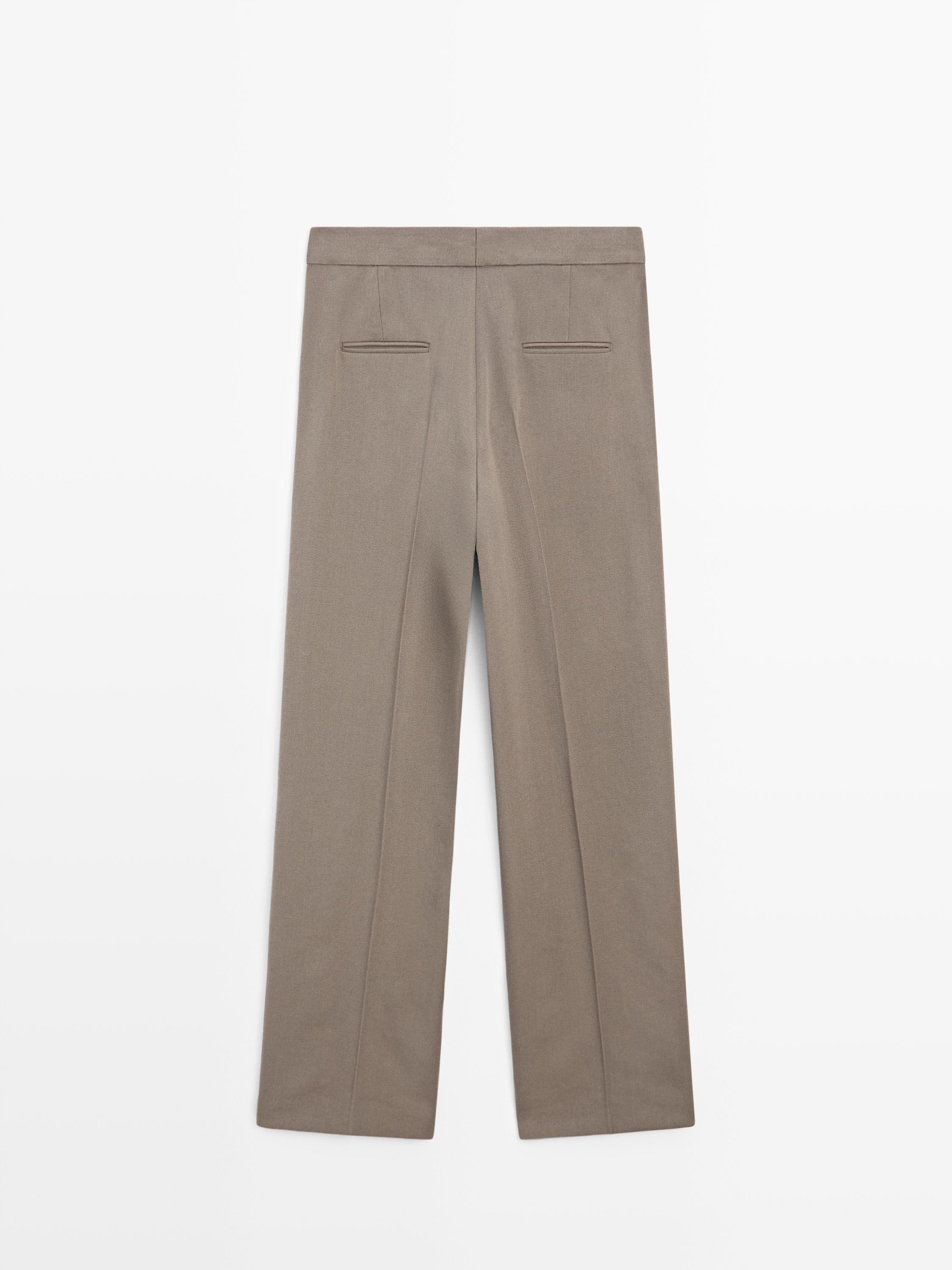 منظر خلفي لبنطال رجالي باللون الزيتي مع جيوب خلفية مزينة بفتحة أزرار وكسرات واضحة.