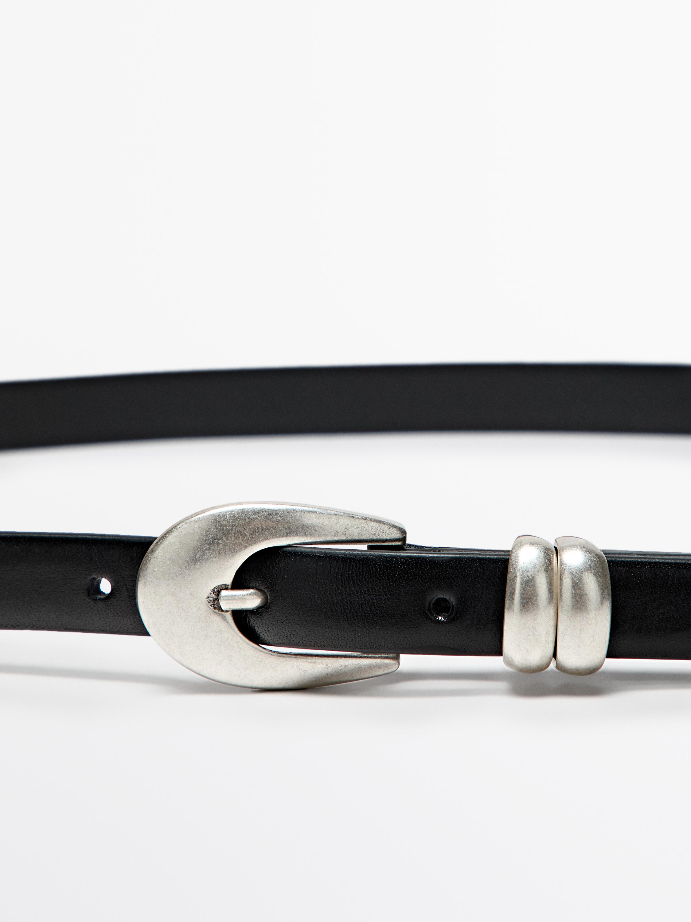 Detail of black belt with silver oval buckle and double metal loop.