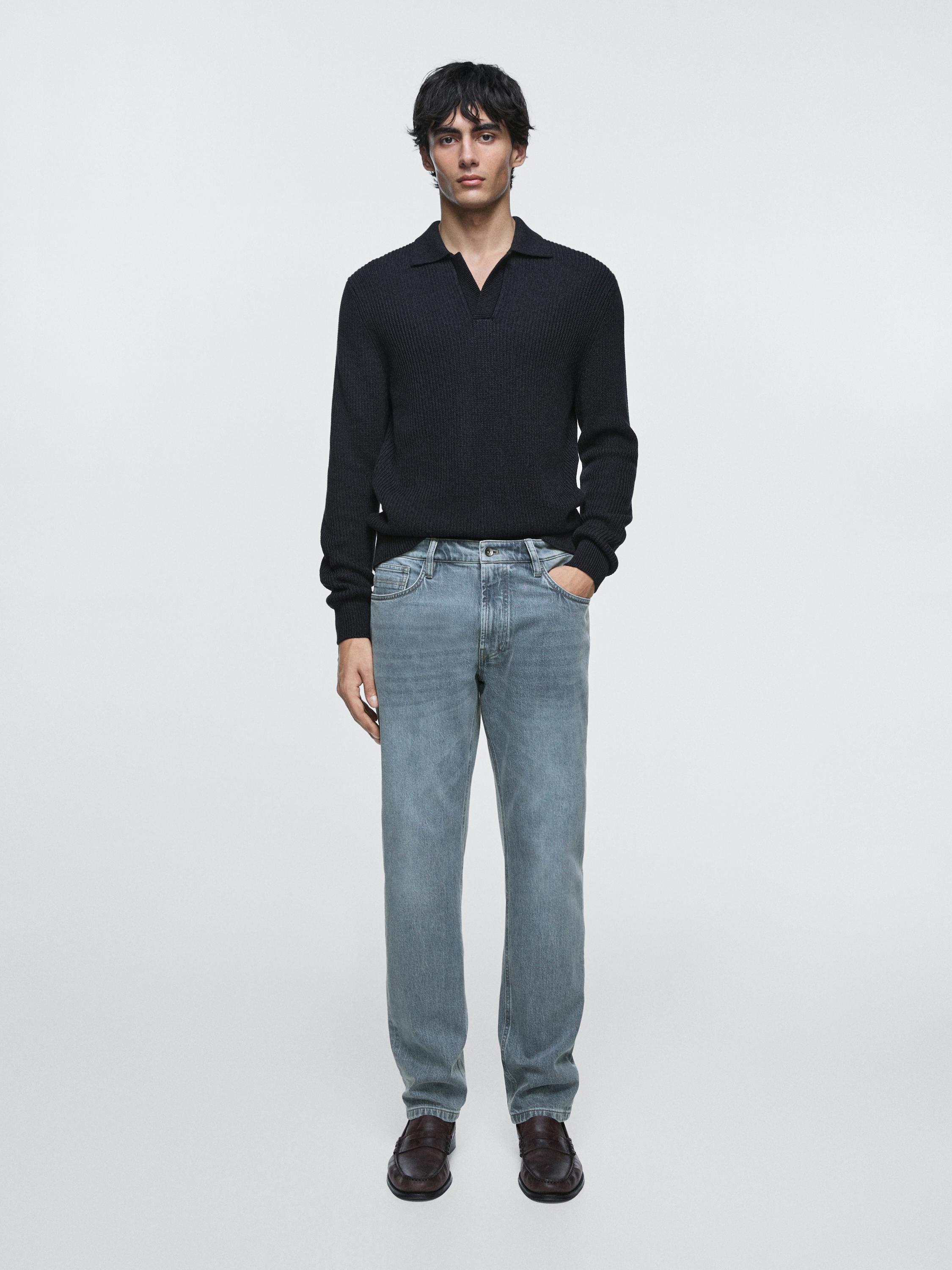 긴팔 검은색 스웨터와 앞뒷주머니가 있는 테이퍼드 컷 인디고 청바지 세트.