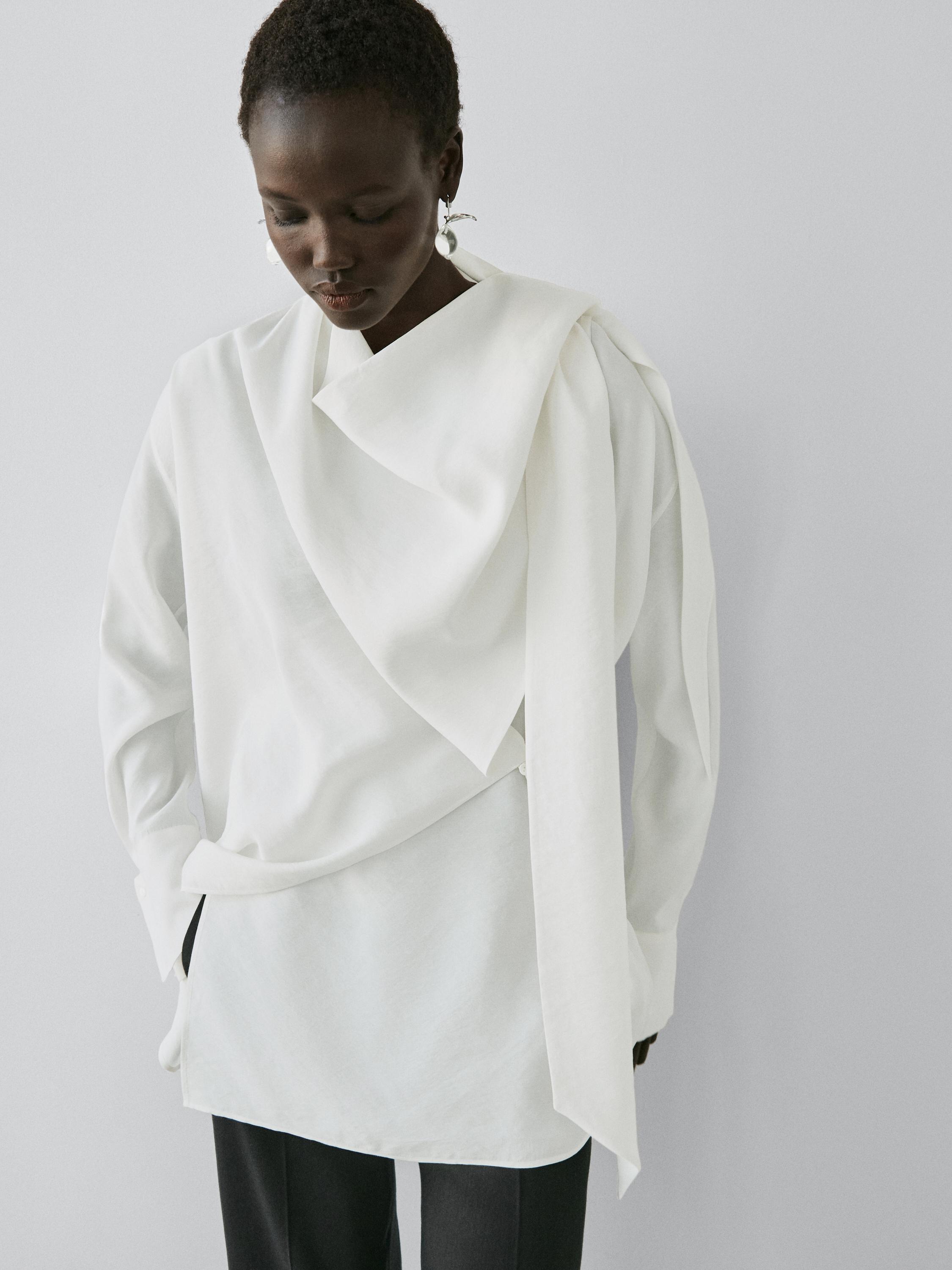 Conjunto de blusa cruda con detalle drapeado y pantalones oscuros.