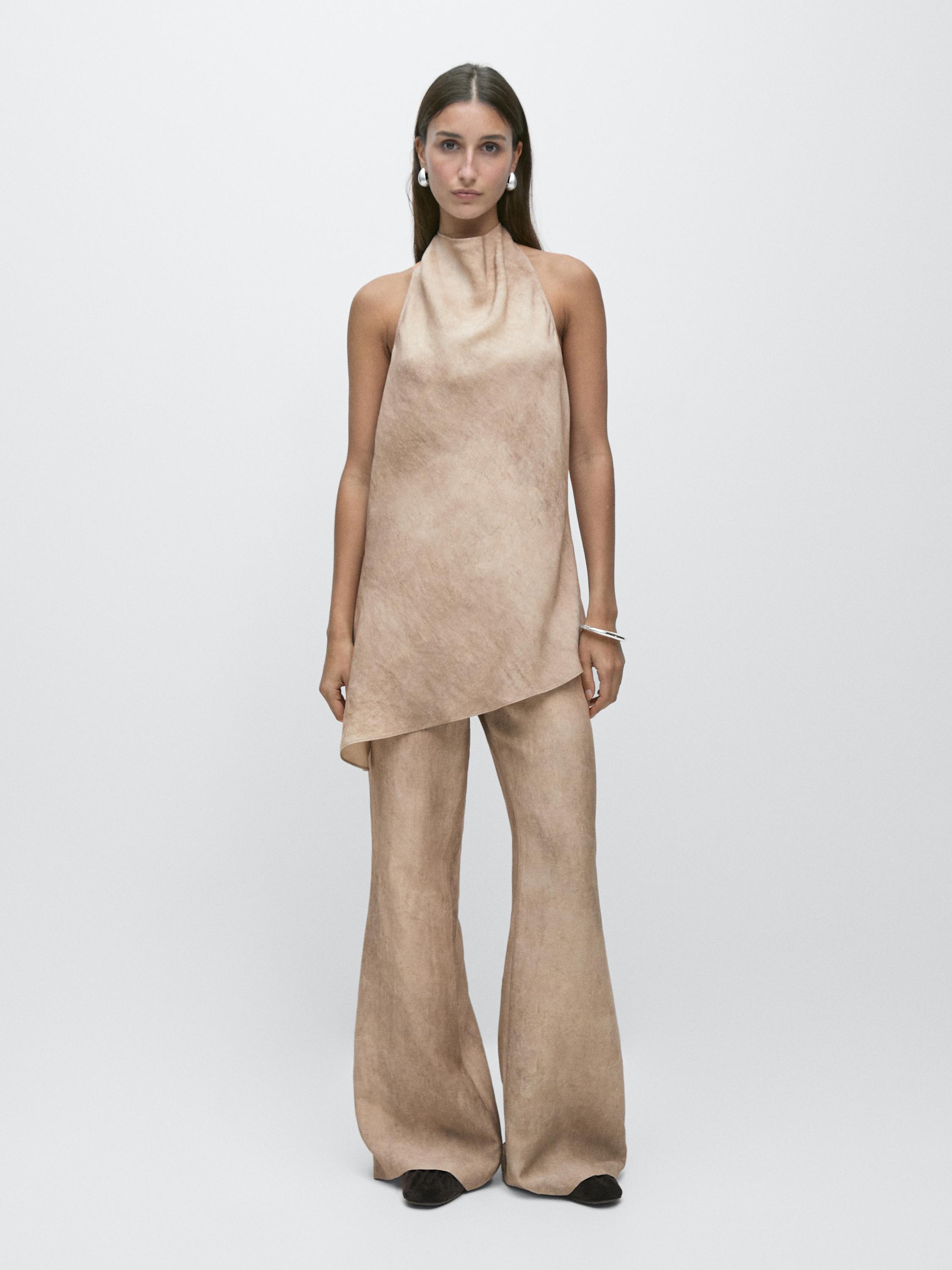 Conjunto de top asimétrico sin mangas y pantalón acampanado color piedra.