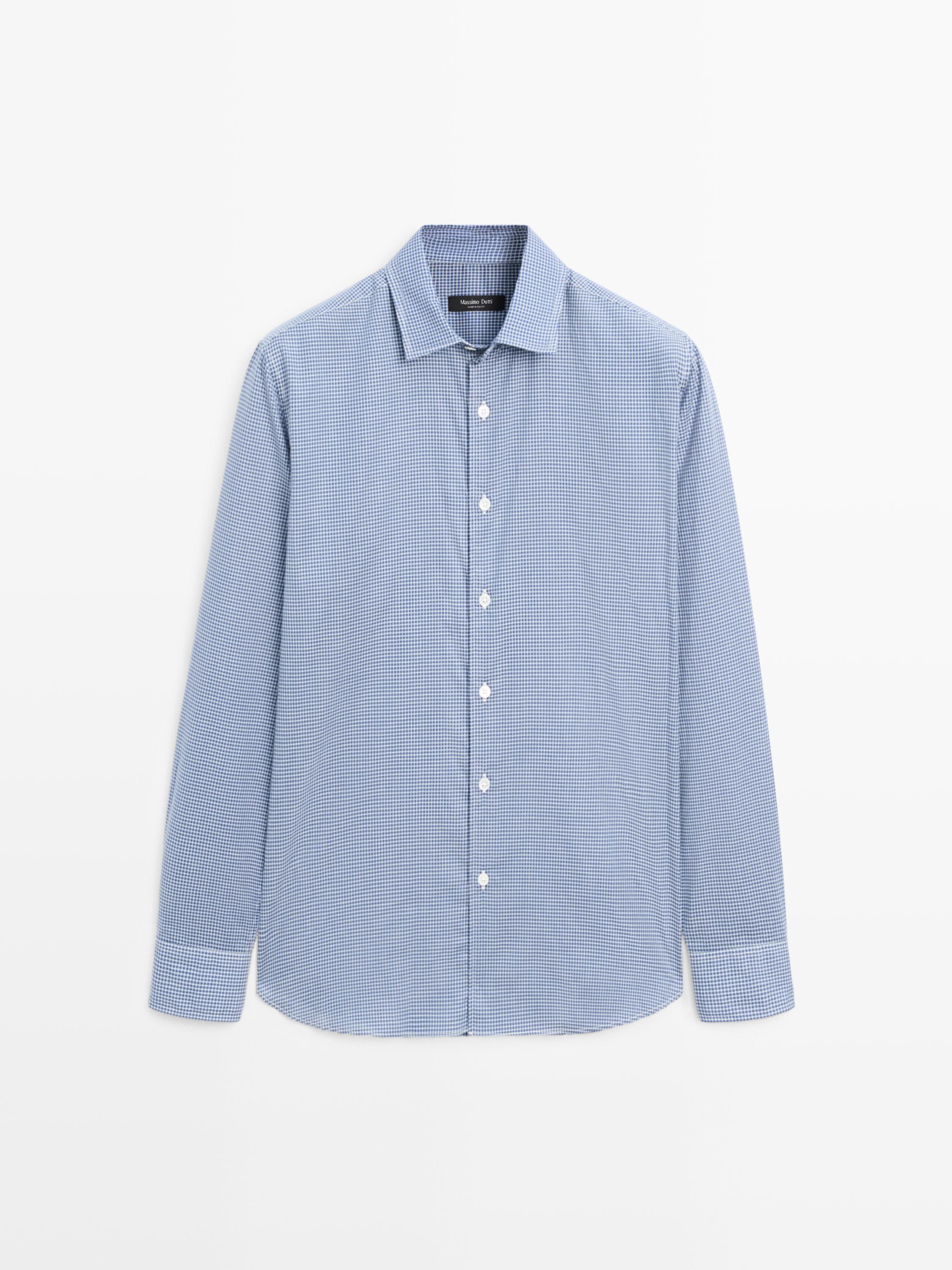 Vue de face d'une chemise bleu canard à manches longues avec boutons blancs et imprimé à petits carreaux.