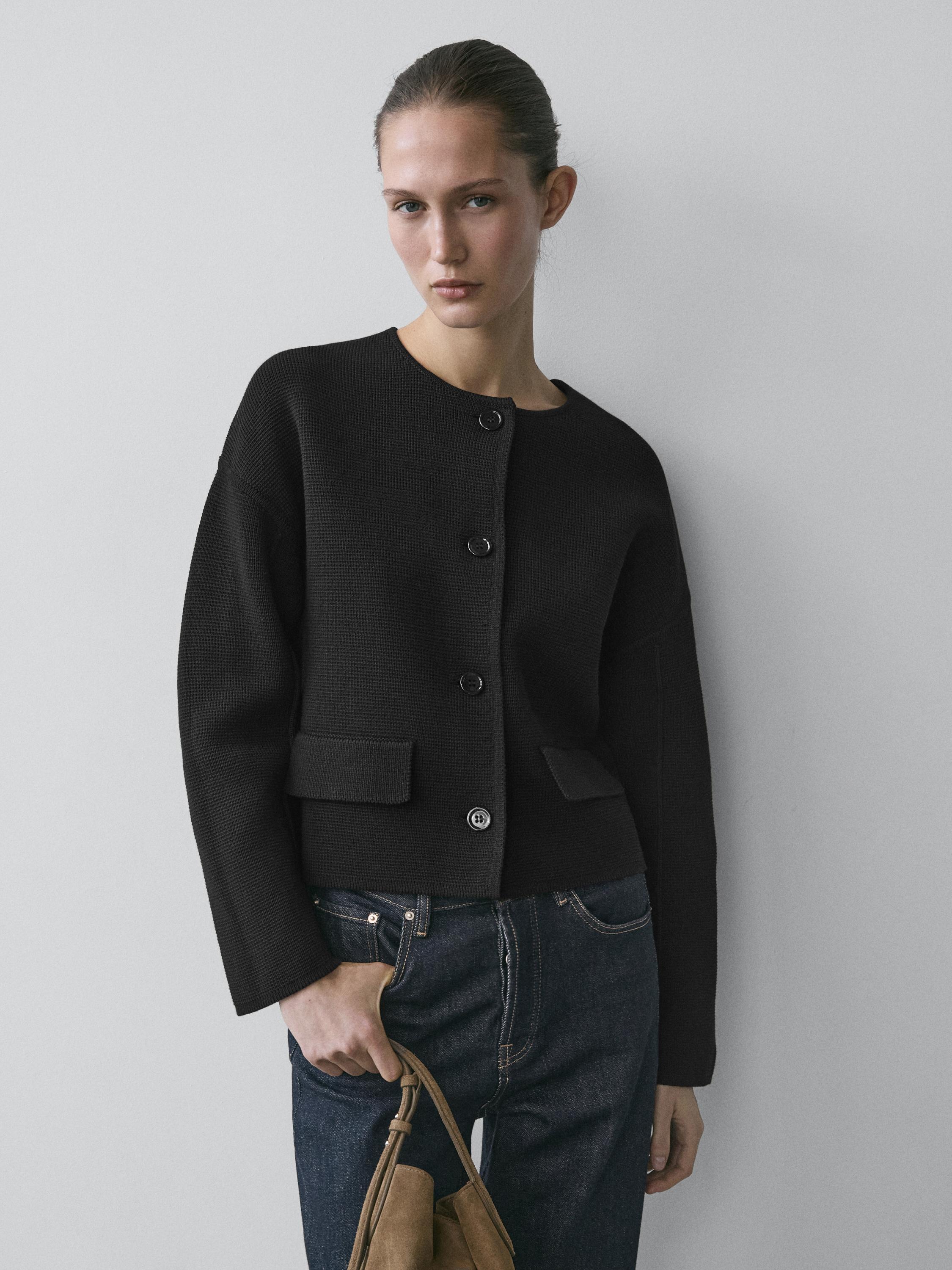 طقم كارديغان أسود بأزرار وجيوب أمامية، مع جينز أزرق داكن.