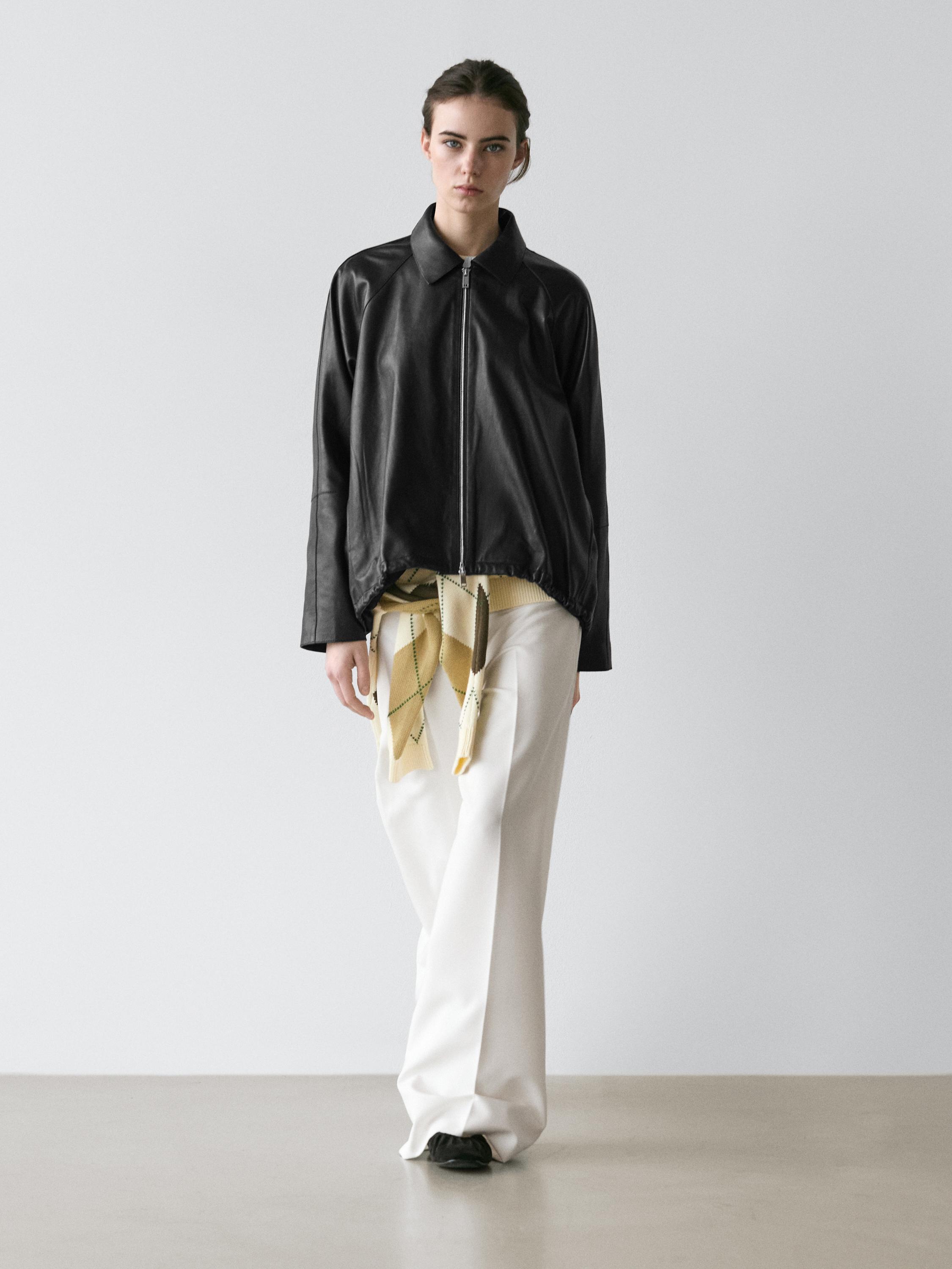 Ensemble de blouson noir zippé et pantalon blanc large.