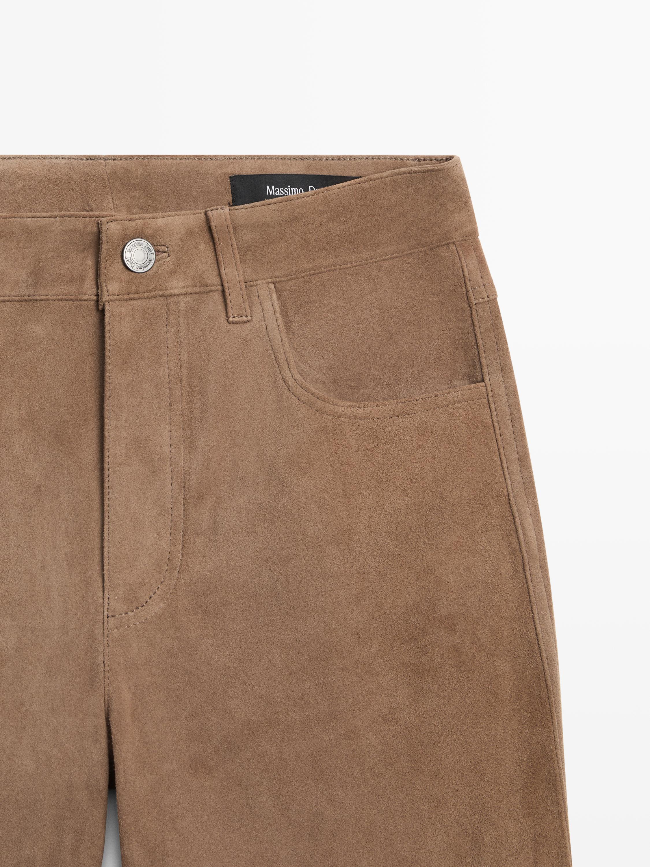 "Metal düğmeli ve ön cepli, vizon rengi pantolonun orta çekimi."