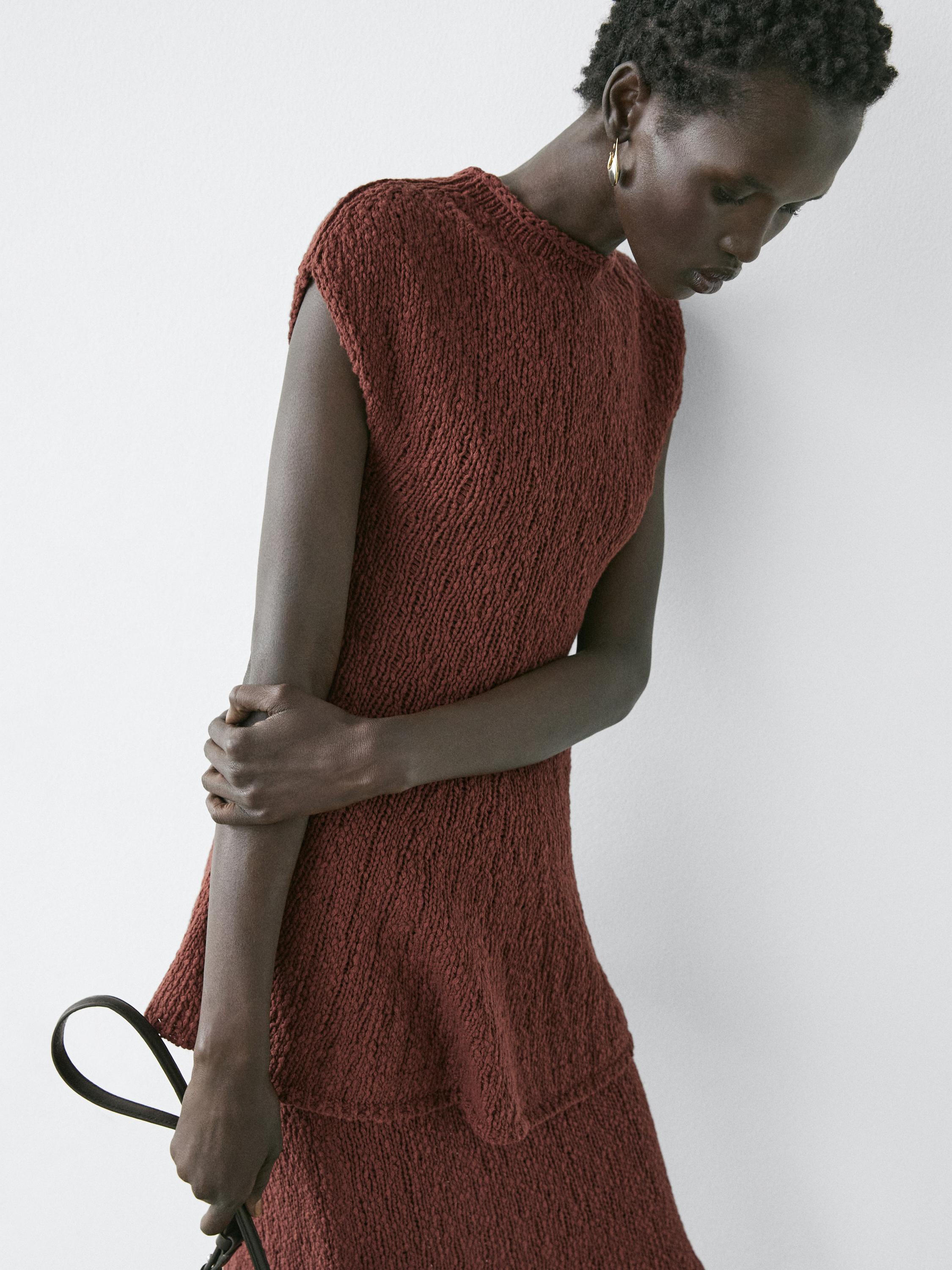 Halbnahe Aufnahme eines ärmellosen, texturierten Kleides in Dunkelbraun.