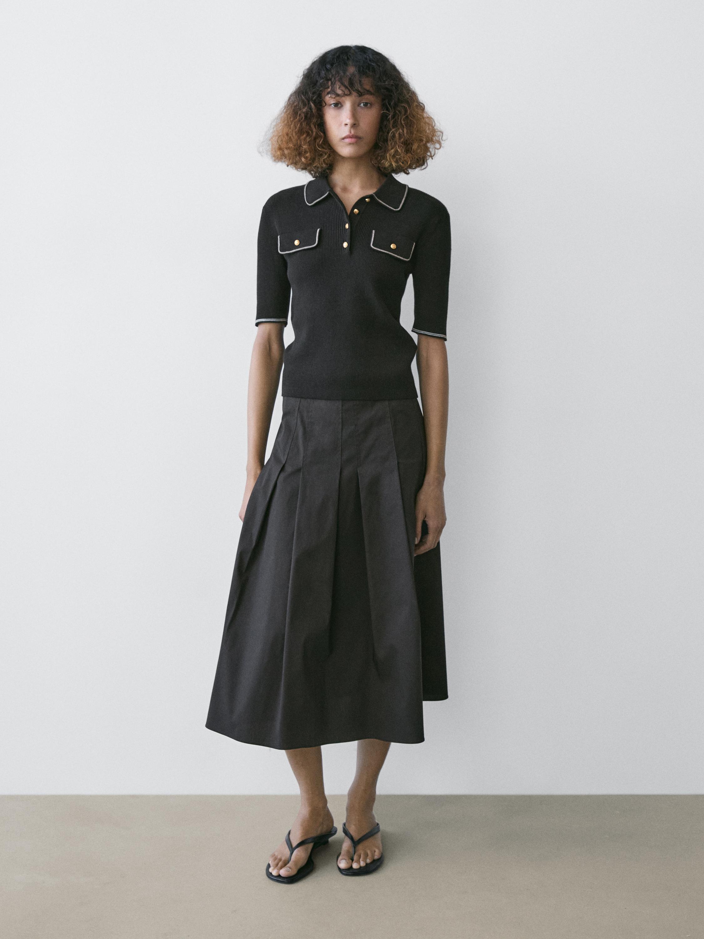 Σετ μαύρο πόλο με μπροστινές τσέπες και μαύρη πλισέ μίντι φούστα.