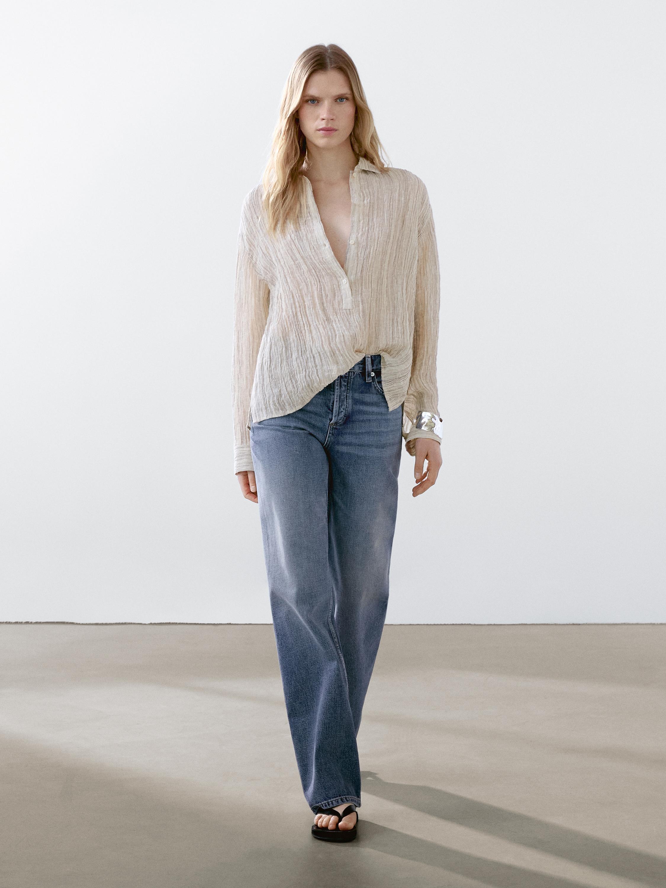 طقم مكون من بلوزة بيج بأزرار وجينز أزرق بقصة مستقيمة.