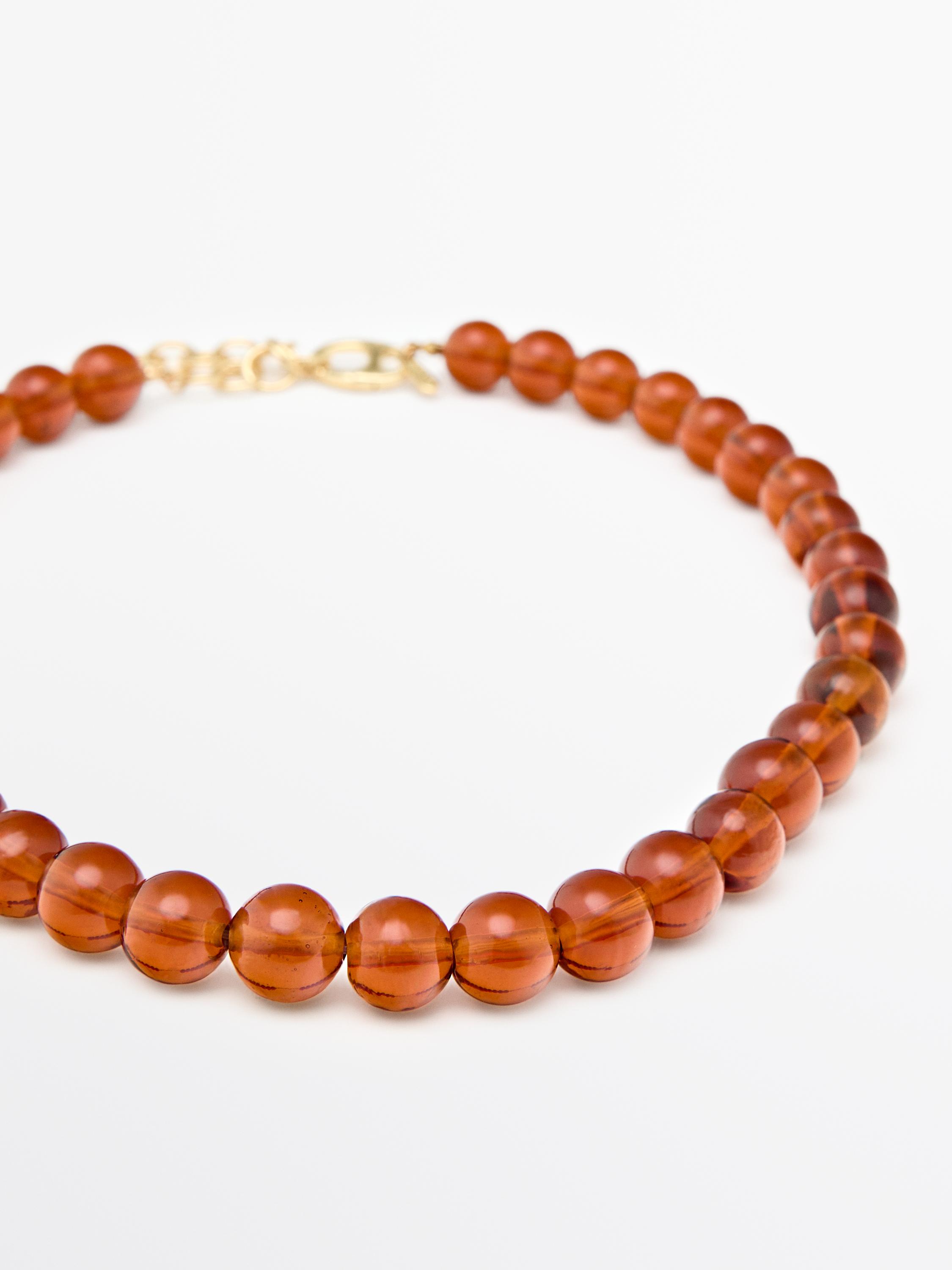 Rød perlehalskæde med guldlås.