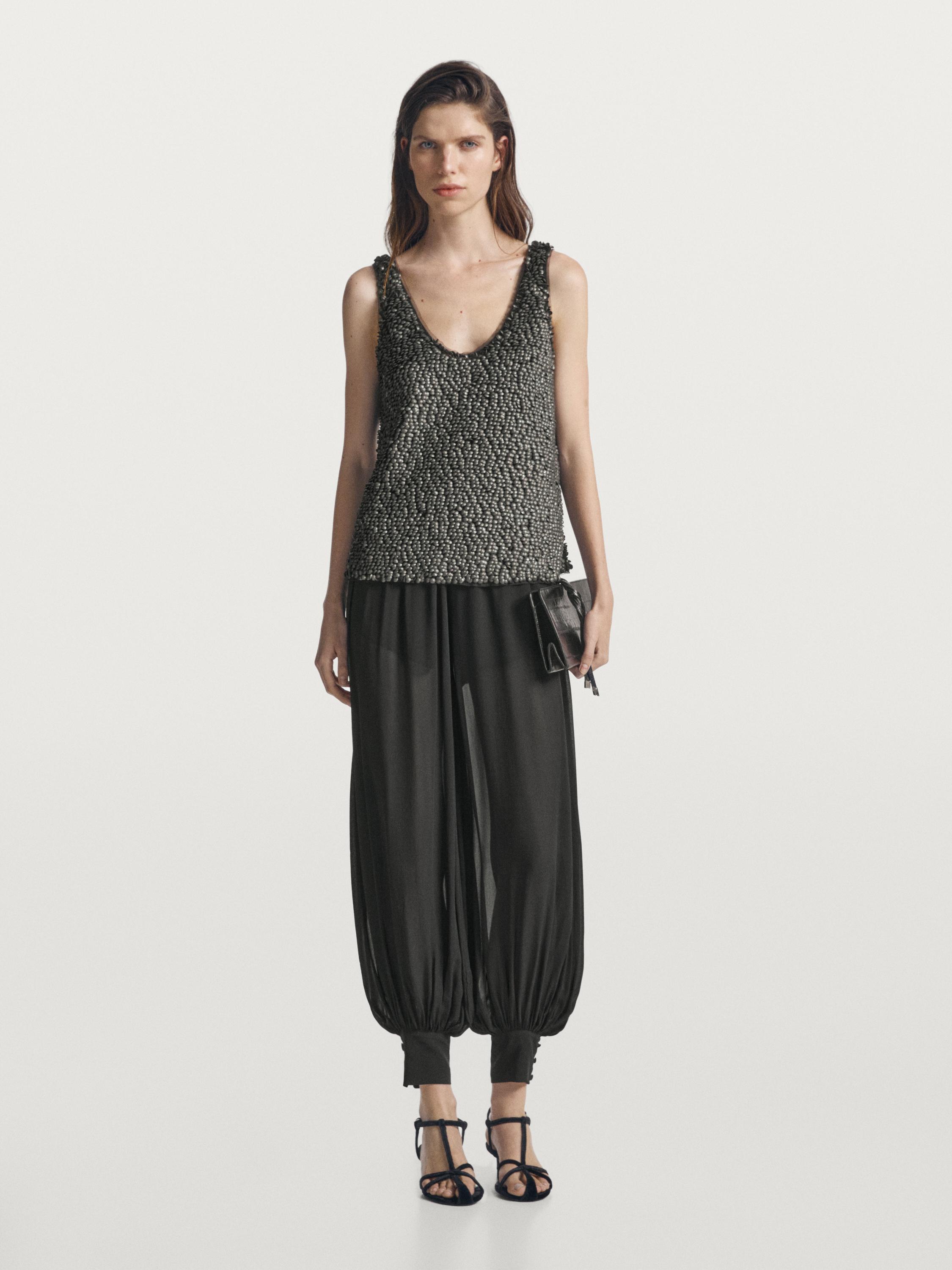 Ensemble comprenant un top gris à perles et un pantalon noir ample à chevilles élastiques.