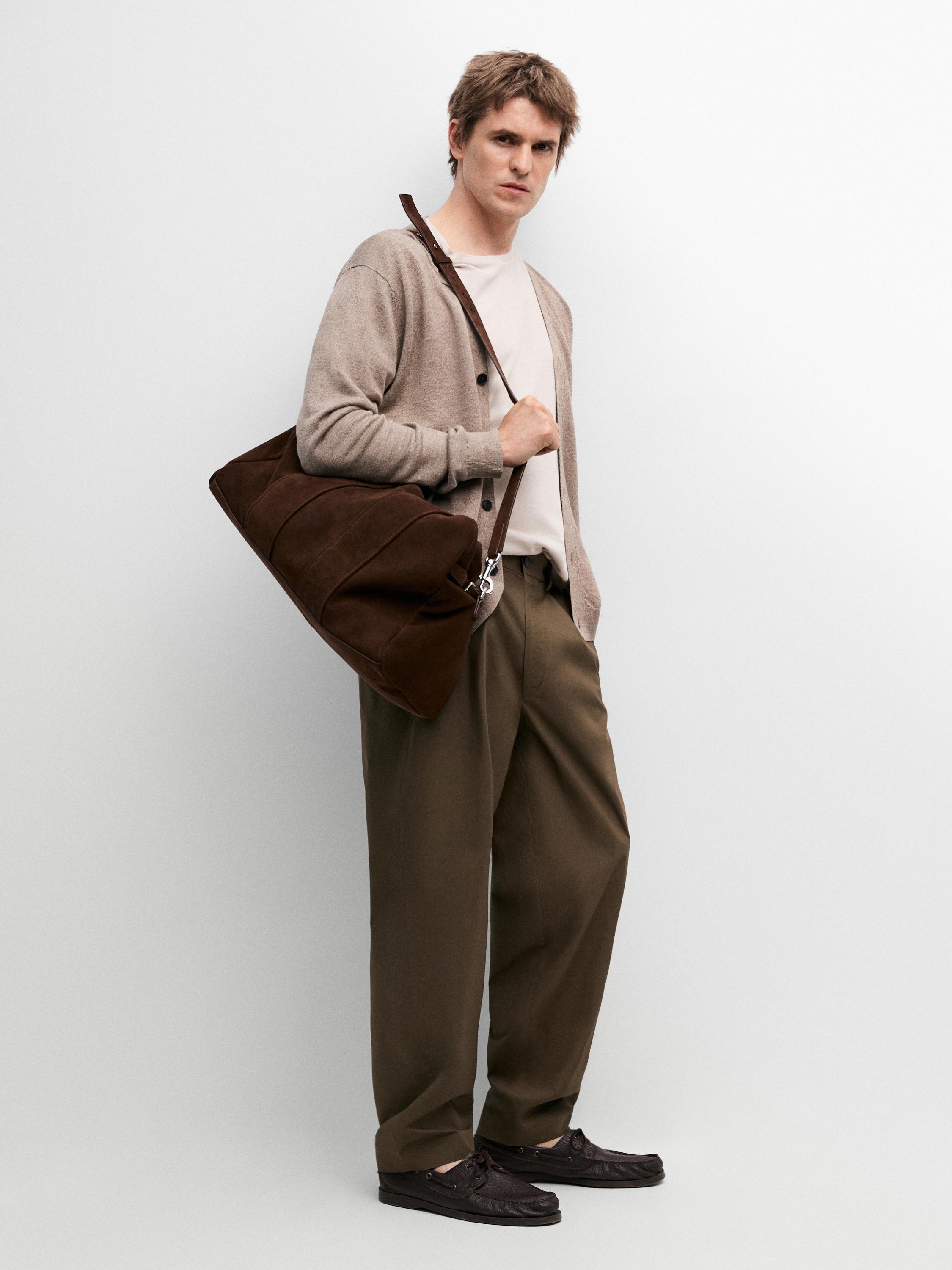 Conjunto de pantalón verde oscuro con doble pinza, camiseta blanca y cárdigan beige con botones.