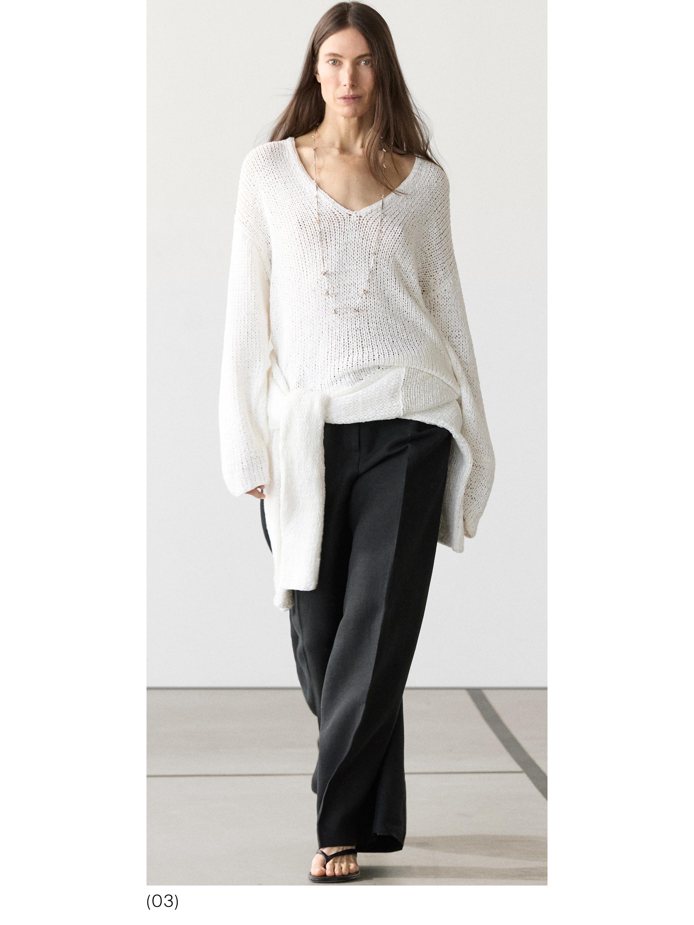 Conjunto de suéter blanco de punto con cuello en V y pantalones negros anchos.