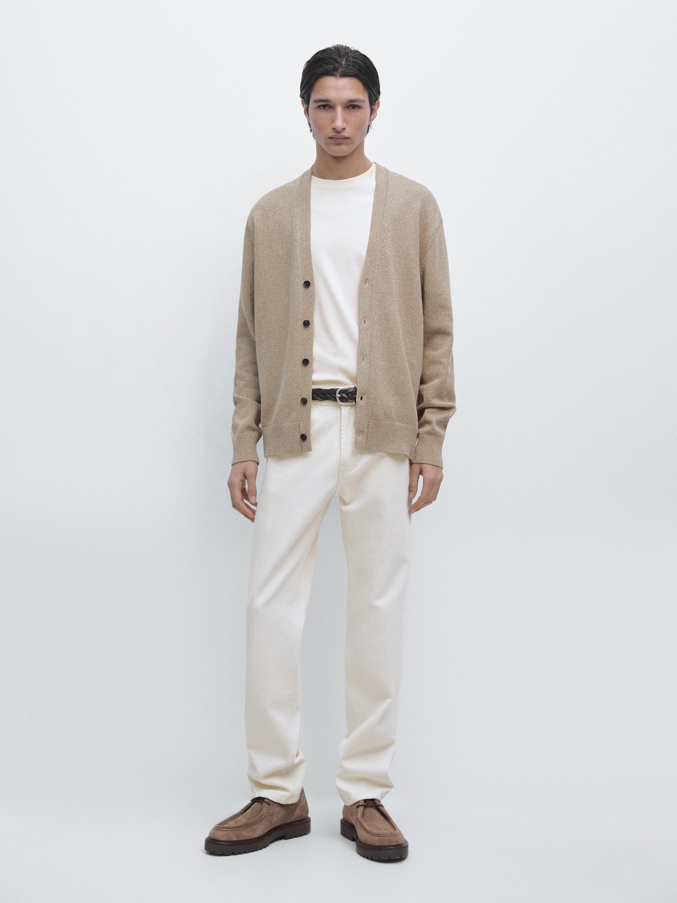 Ensemble composé d'un cardigan verdâtre boutonné, d'un t-shirt blanc, d'un pantalon crème et de chaussures marron.