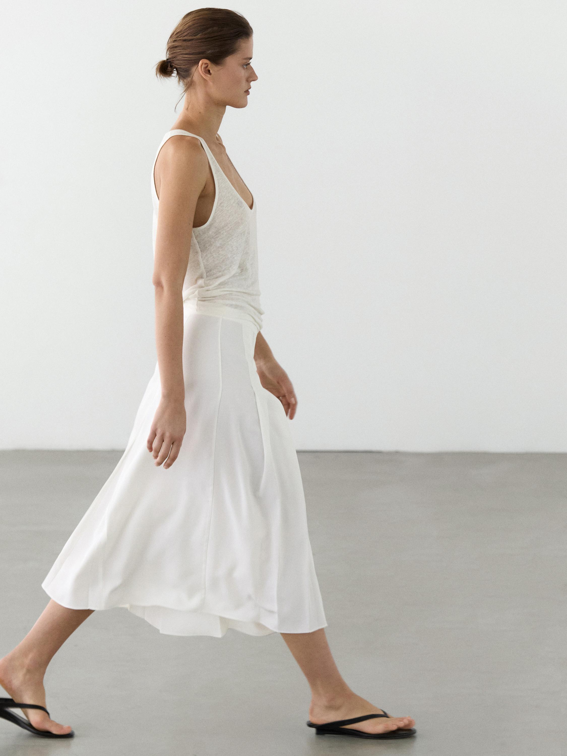 Conjunto de falda midi blanca con tablas y camiseta sin mangas blanca.